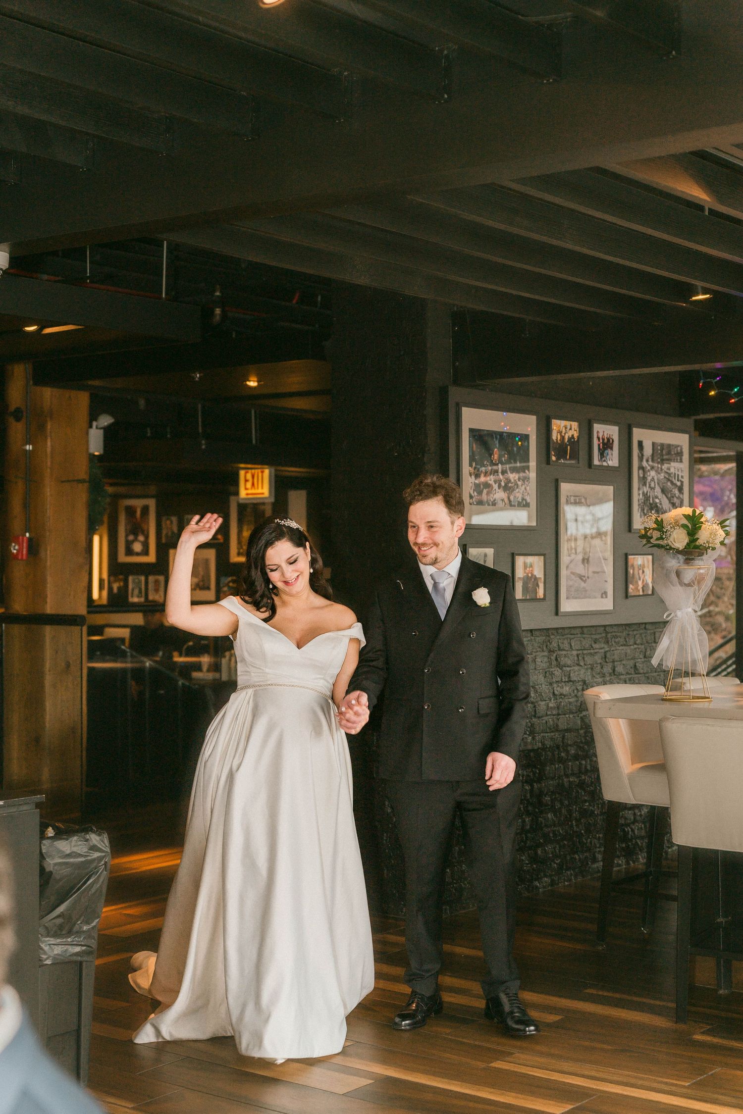 Bride and groom make joyful grand entrance into rustic wedding reception venue together.