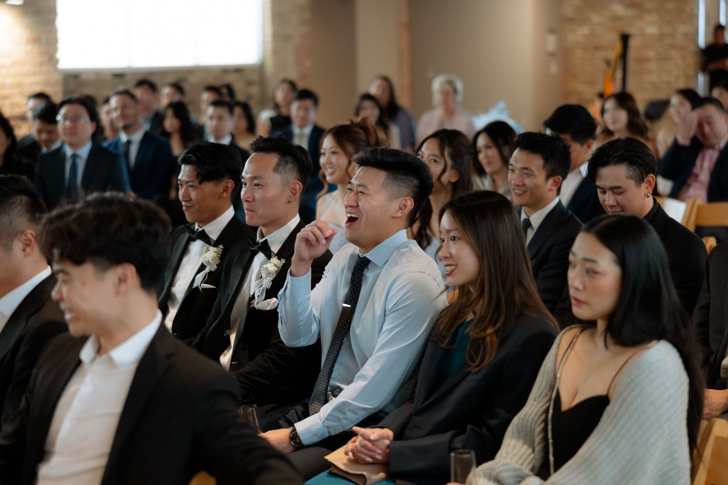 Guests smiling and laughing during a wedding ceremony inside a modern church venue.