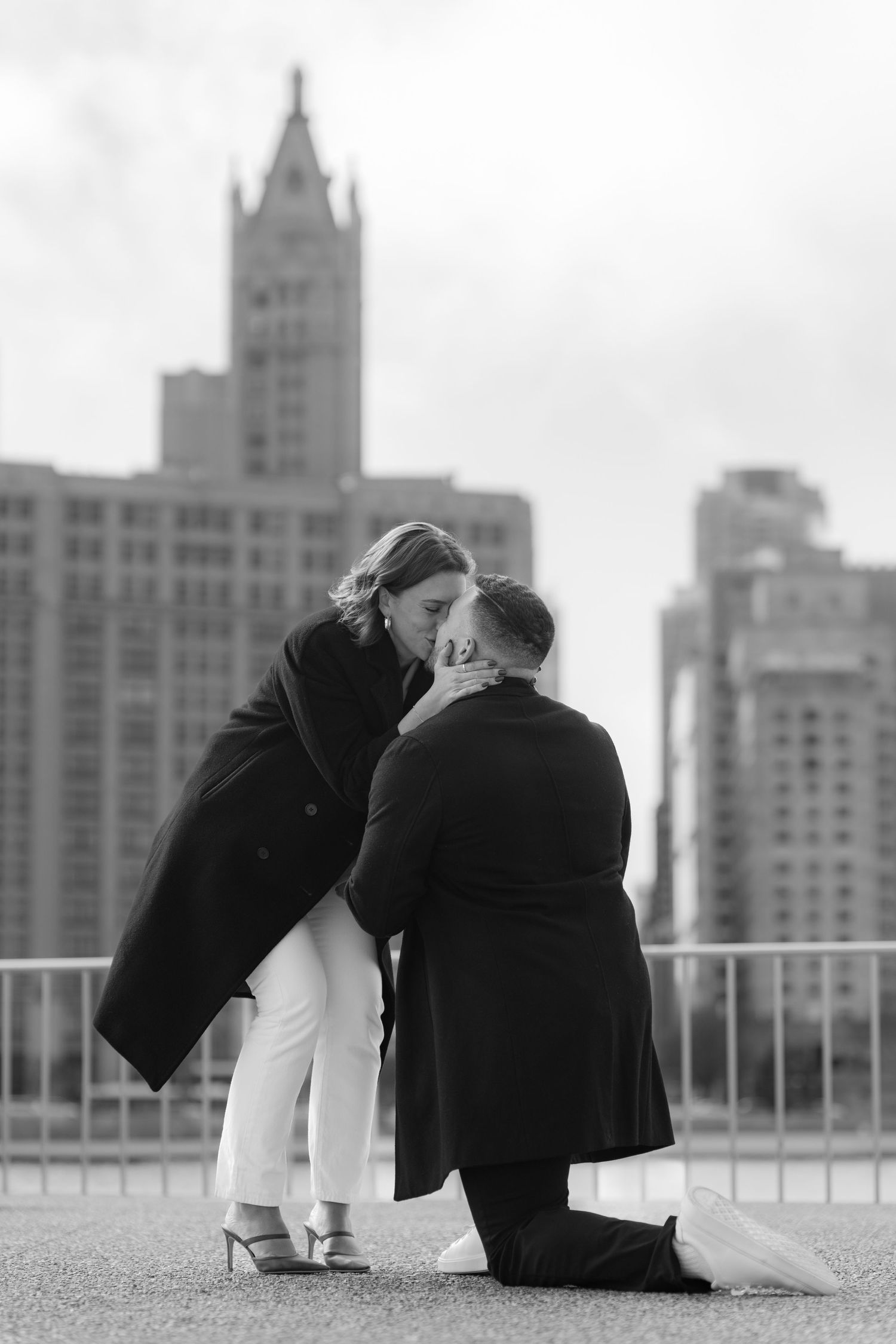 Tender black and white moment of couple connecting after marriage proposal with Chicago skyline backdrop.