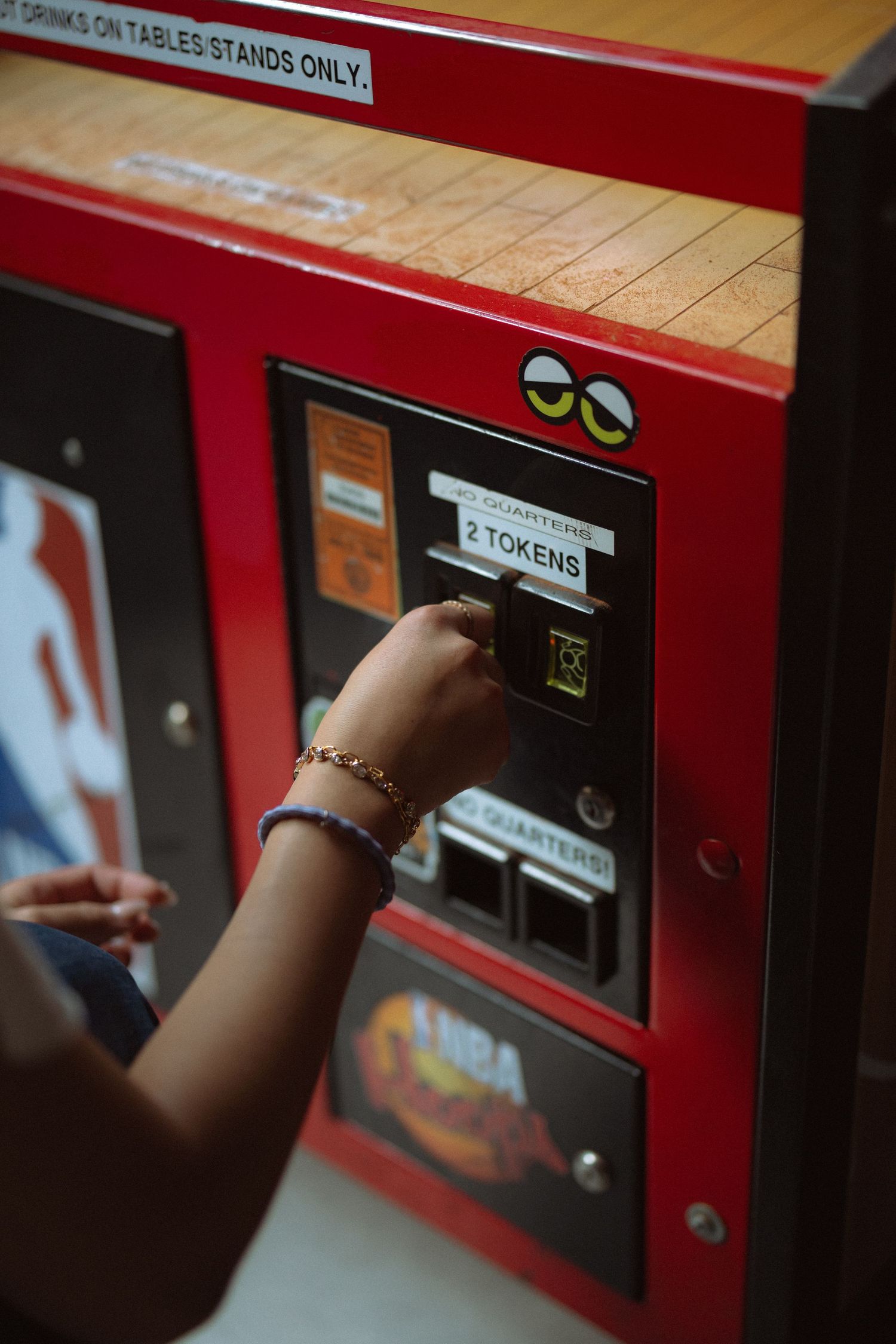 Person inserting quarters into a red token exchange machine at an arcade.