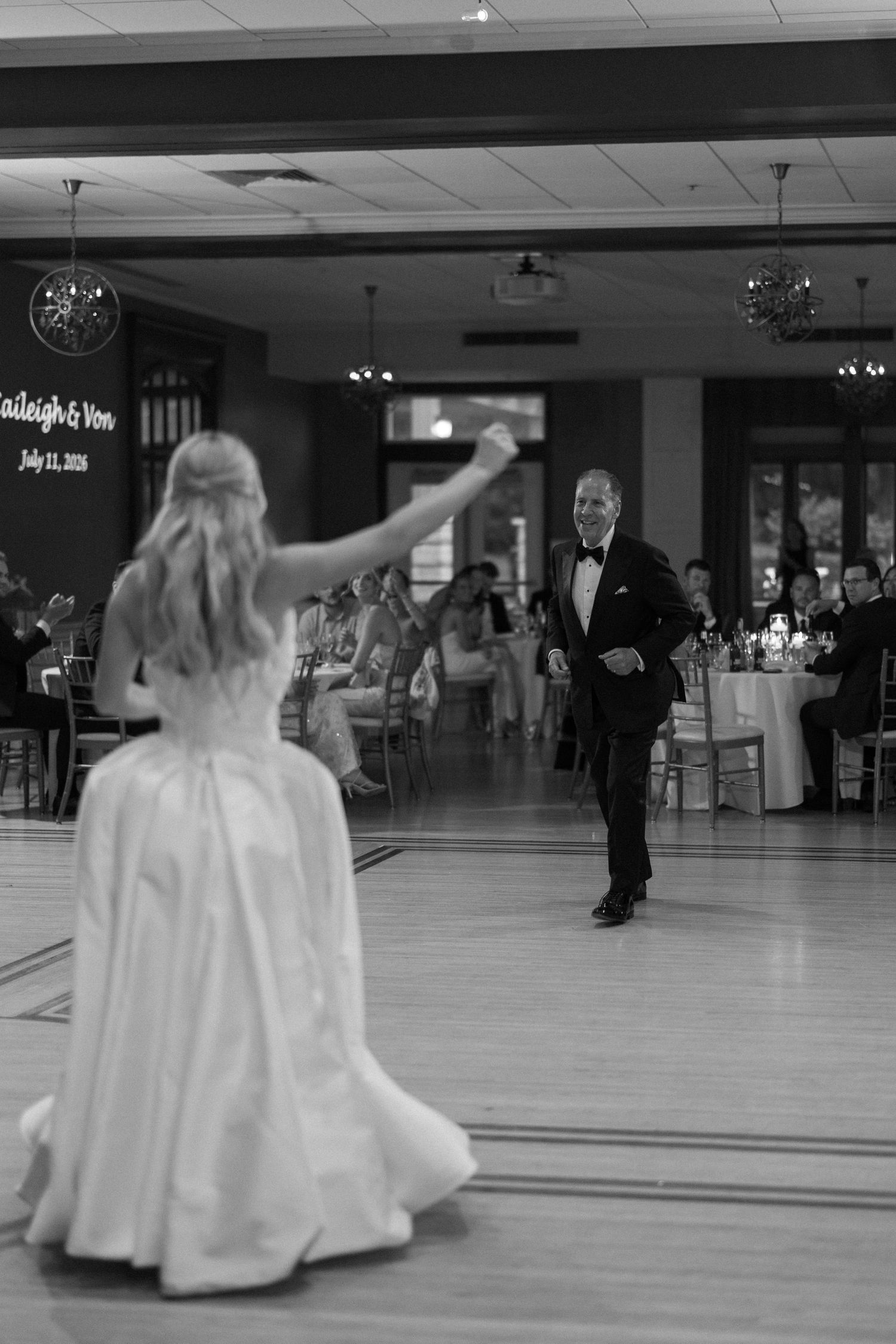 Black and white photo of bride and father sharing emotional dance on wedding reception dance floor.