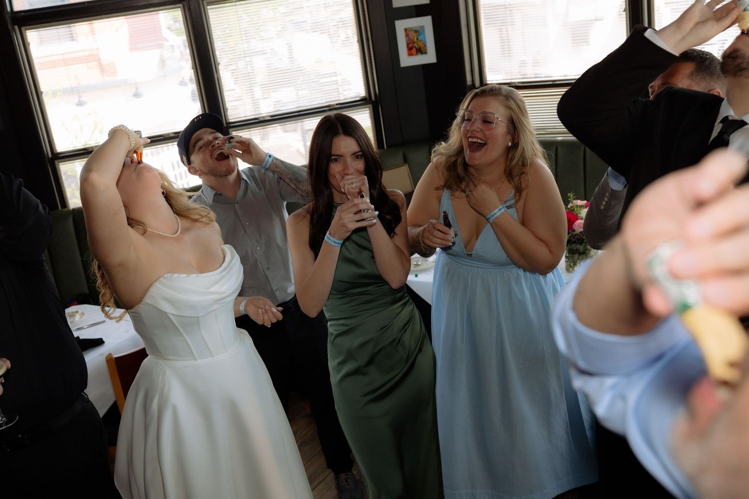 Bride and bridesmaids dancing and celebrating joyfully at a wedding reception indoor venue.
