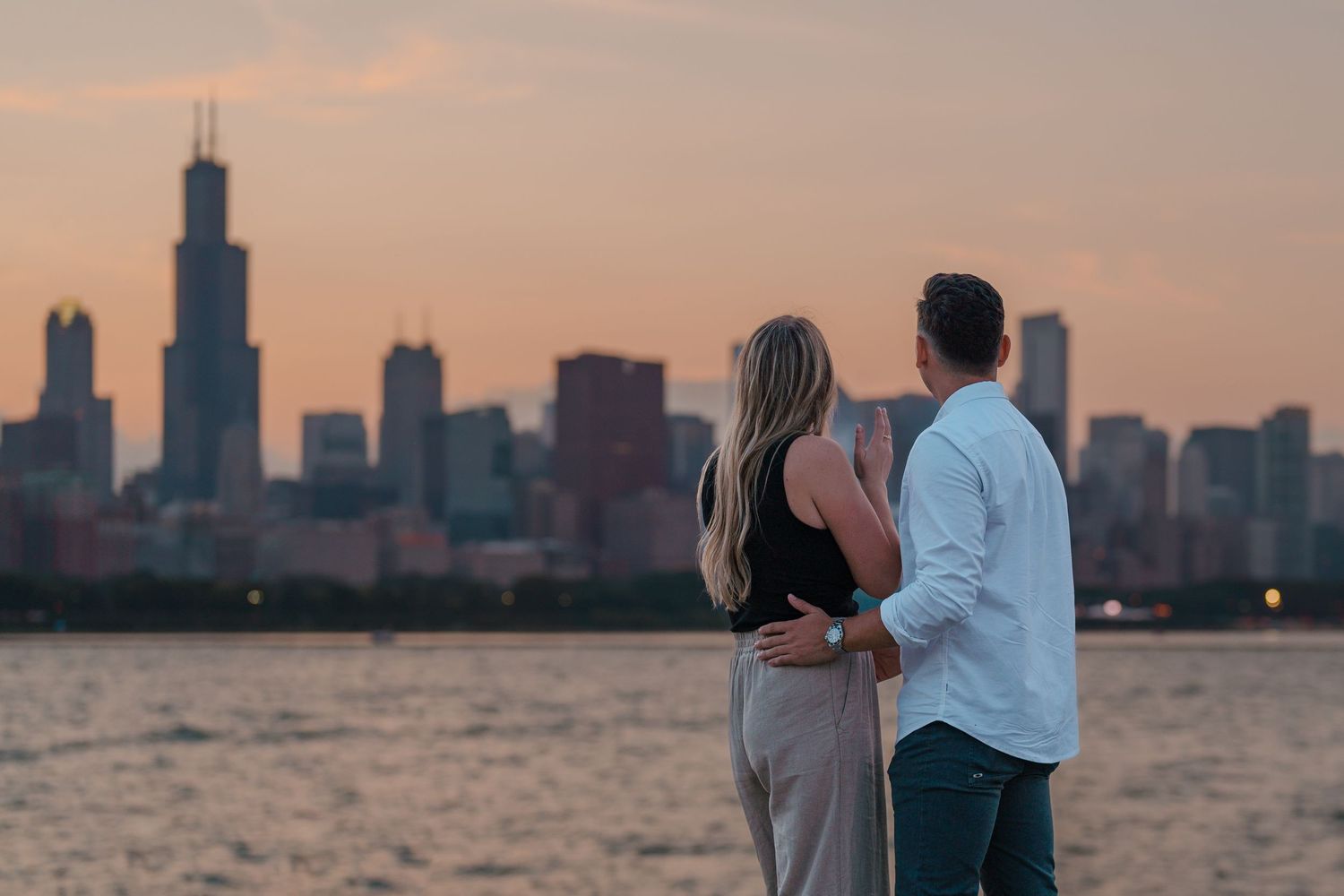 Couple embracing while gazing at the stunning Chicago skyline at golden hour from the lakefront.