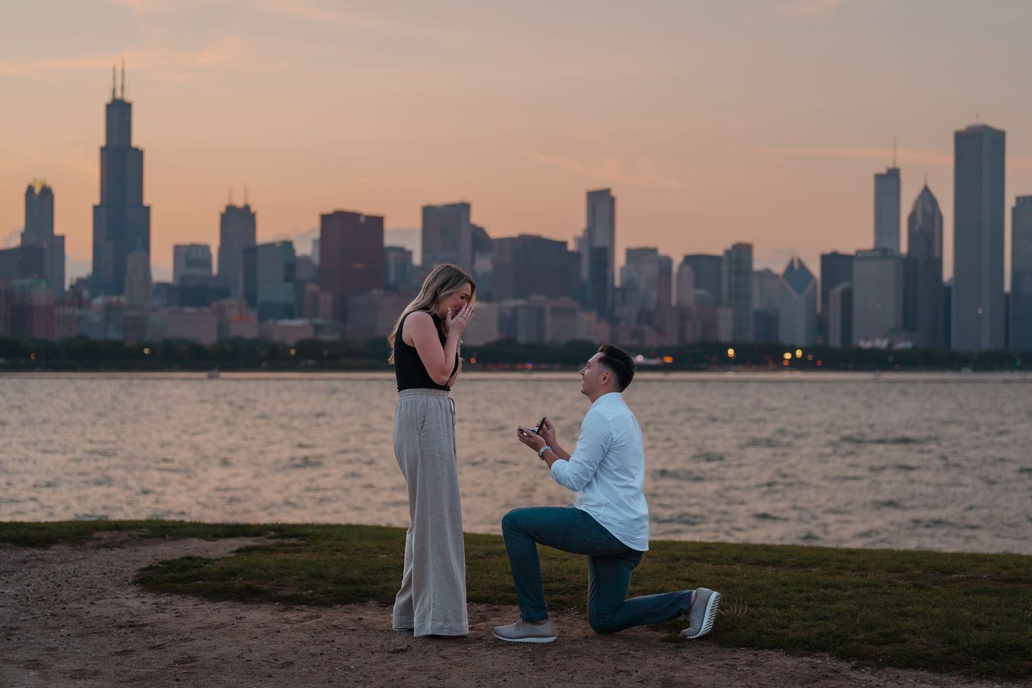 Couple during marriage proposal at Chicago lakefront with stunning sunset skyline view.