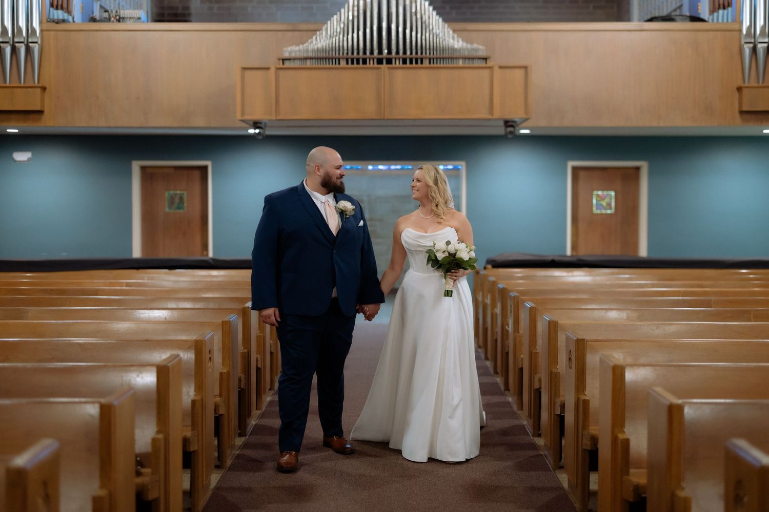 Bride and groom walking hand in hand down the aisle of a church after their wedding ceremony.
