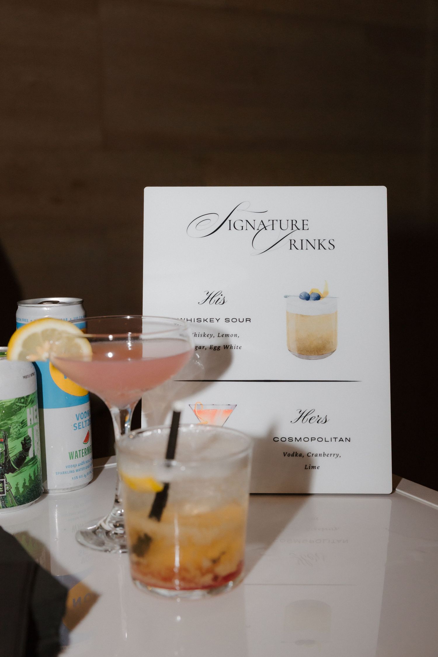 Wedding signature drinks display with His whiskey sour and Hers cosmopolitan cocktails beside a decorative menu sign.