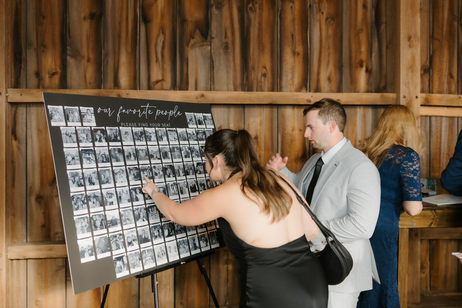 Wedding guests viewing a black and white photo display board labeled our favorite people at reception.