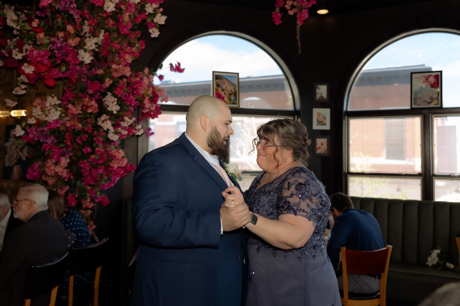 Couple sharing a tender moment at a wedding reception venue adorned with pink floral decorations.