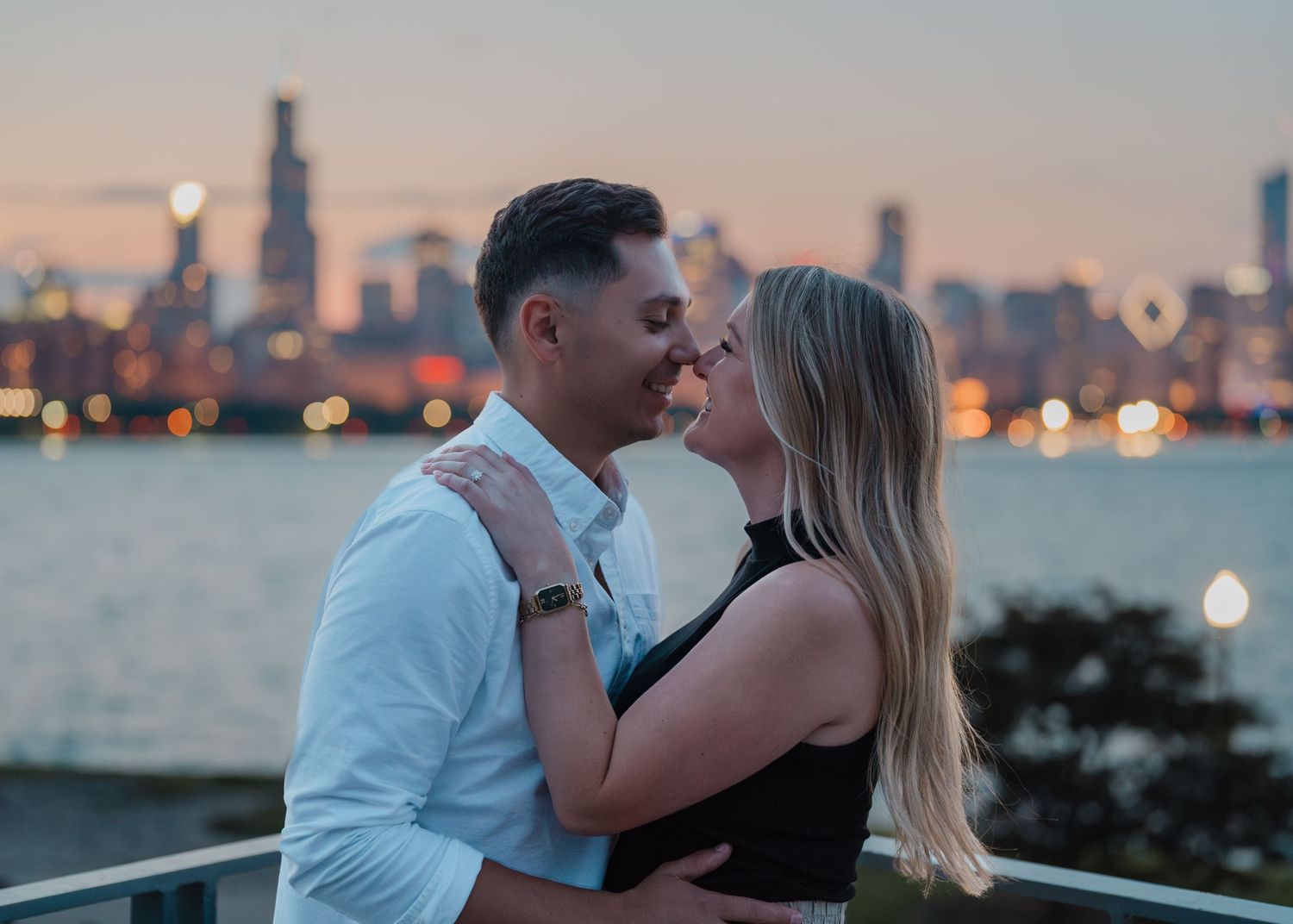 A romantic couple shares an intimate moment with the Chicago skyline glowing at sunset behind them.