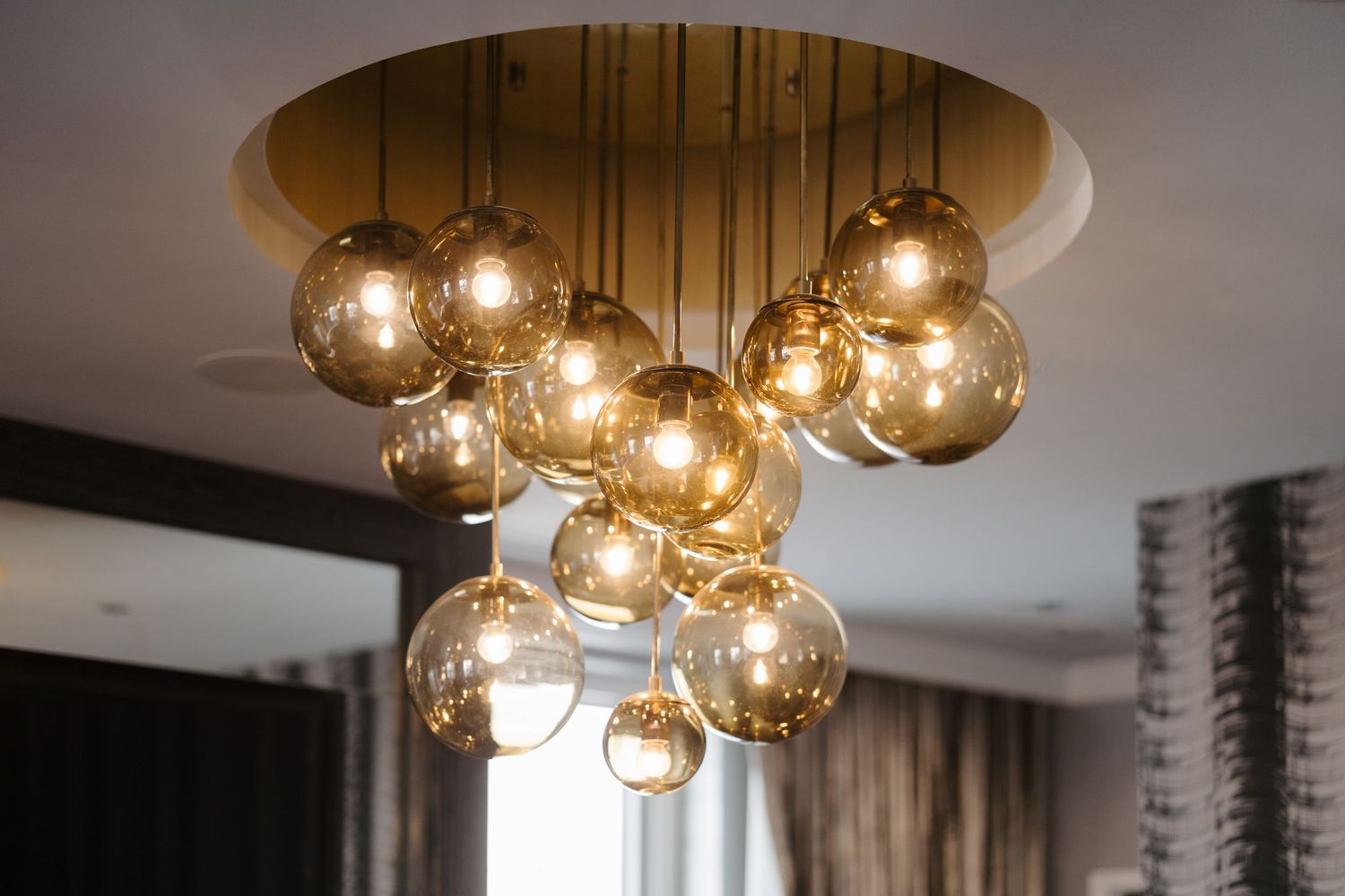 Modern ceiling light fixture with amber glass globe pendants hanging at varying heights.