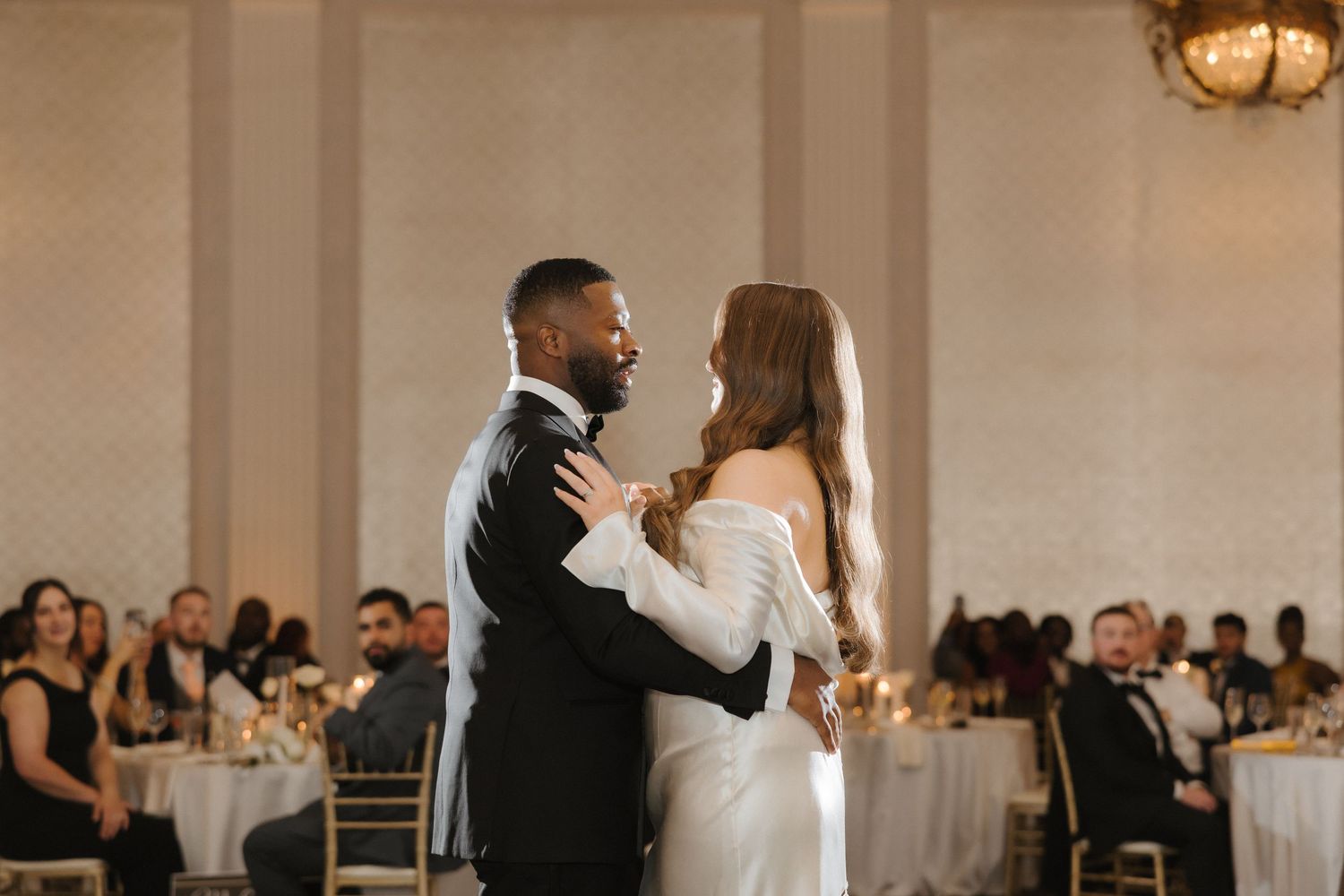 Bride and groom share their first dance in an elegant ballroom during a wedding reception.