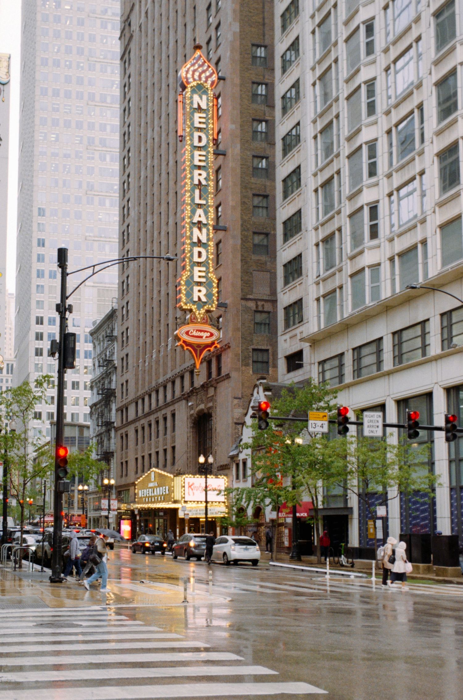 Nederlander Theatre marquee glows on a rainy day in Chicago's Loop theater district, reflecting light on wet streets.