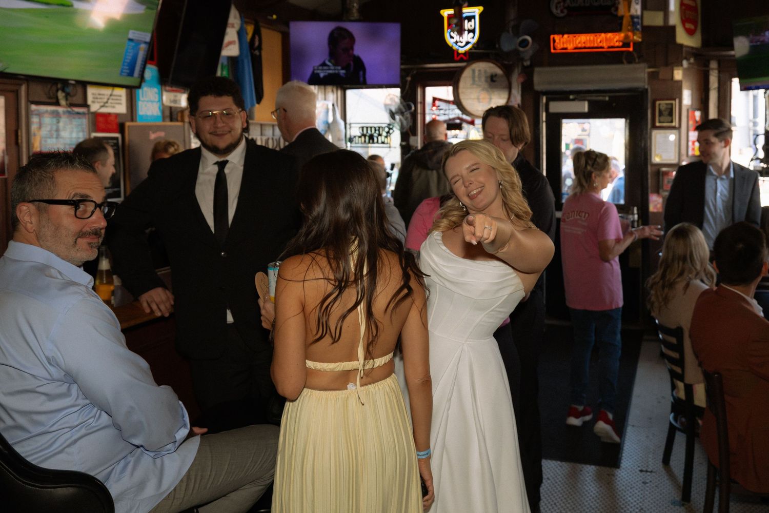 Bride in white dress dancing with guests at a bar wedding reception celebration.
