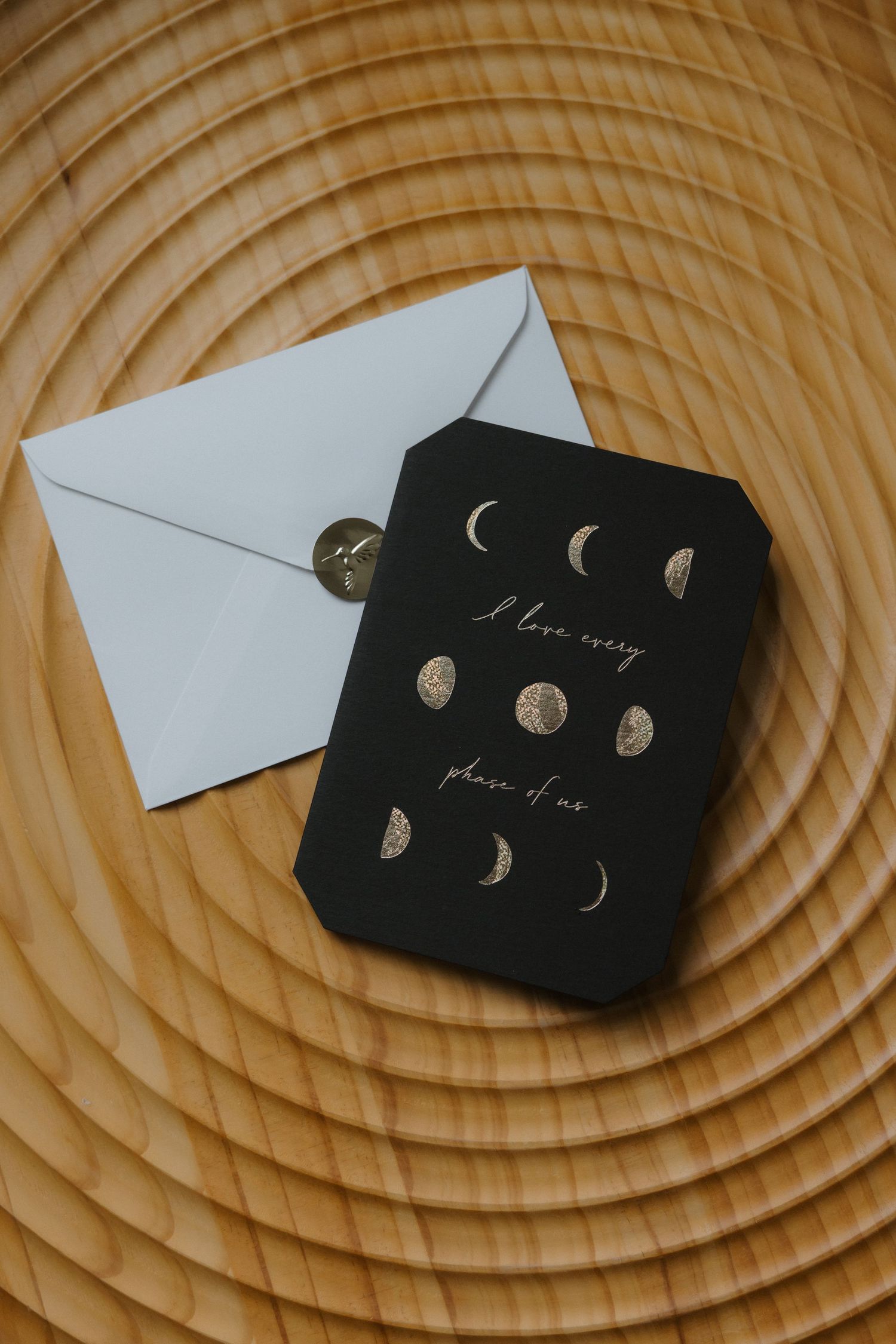 Black wedding card with moon phases design reading I love every phase of you with white envelope.