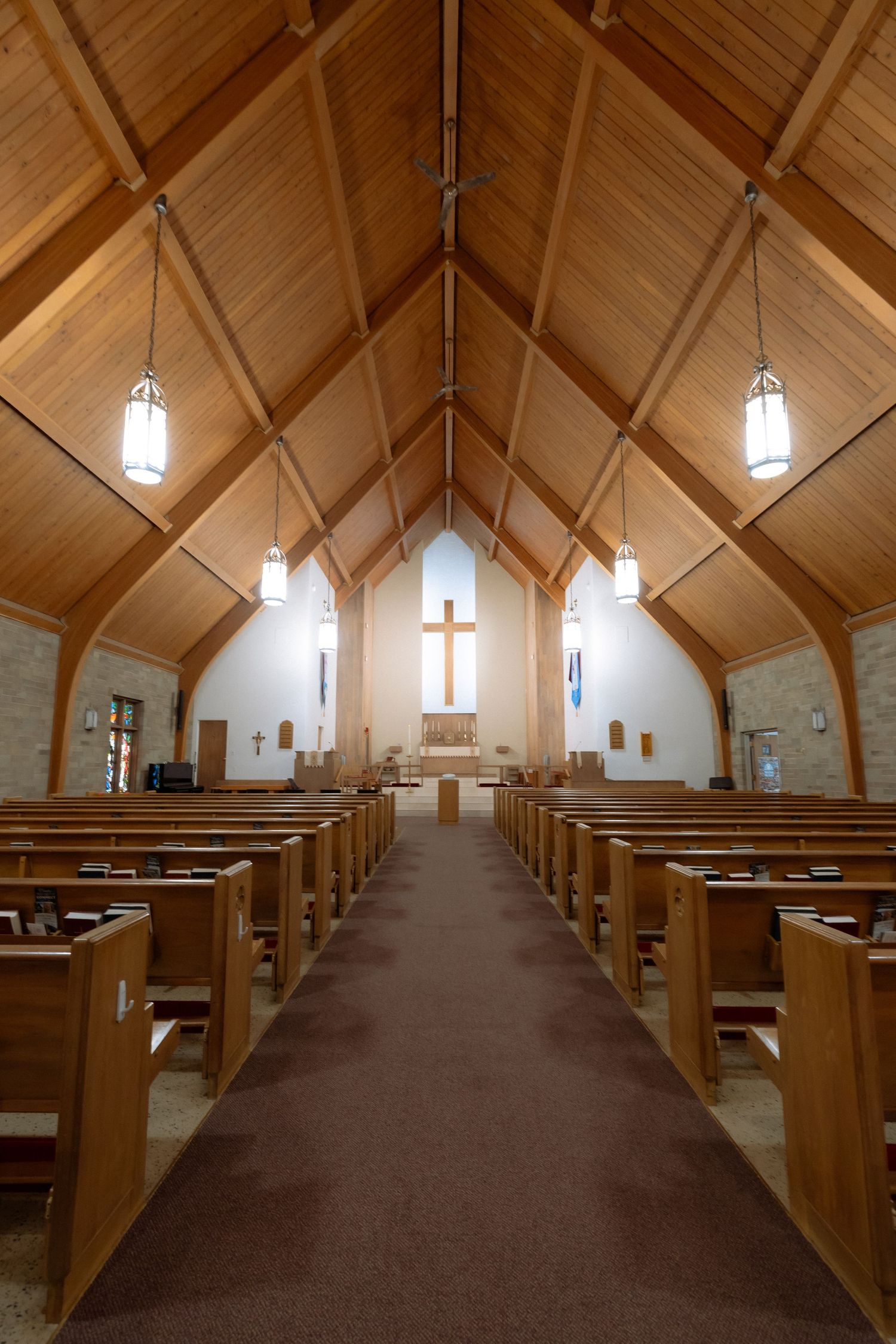 Interior of a serene church with wooden pews, vaulted ceiling, and a cross at the altar.