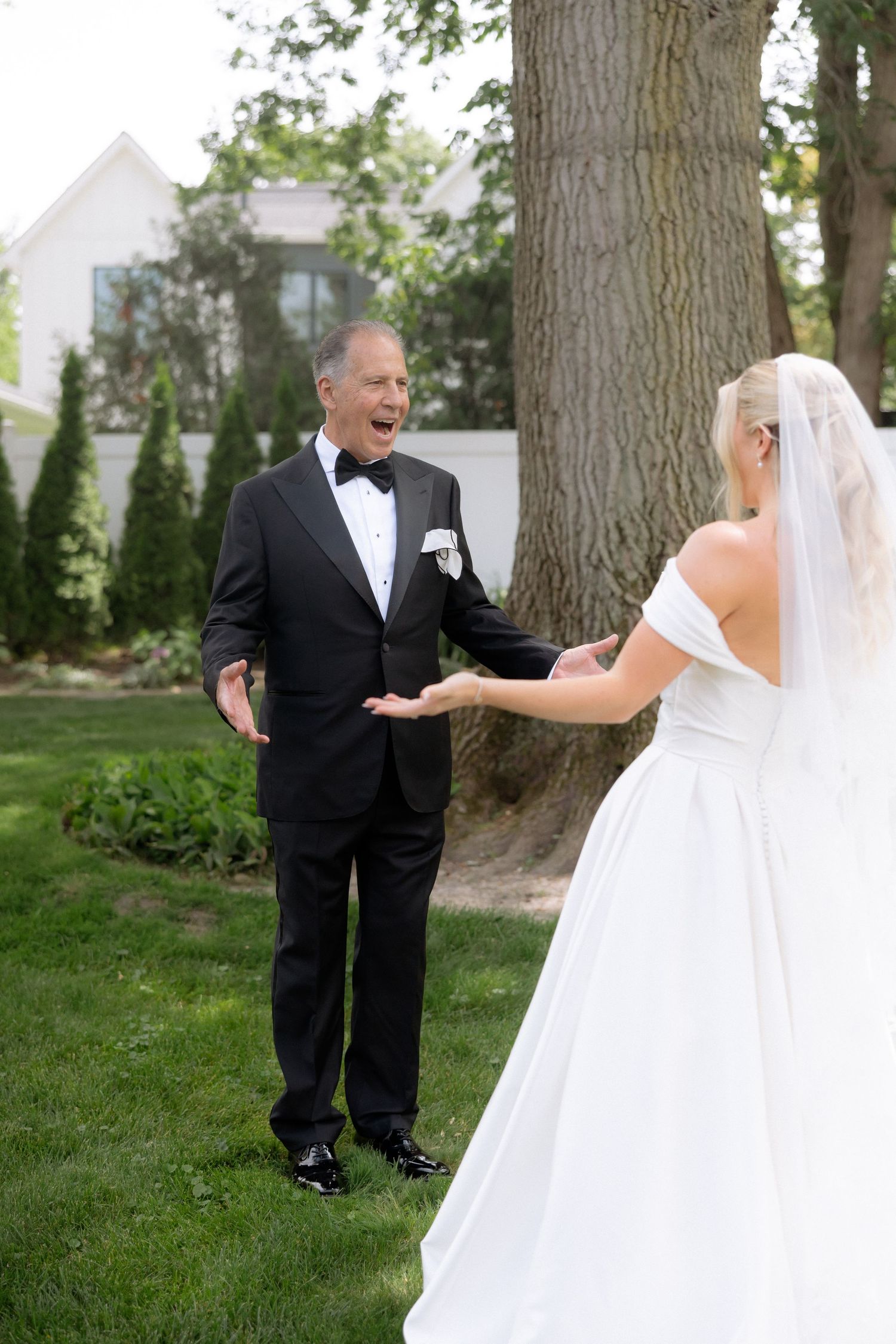 Emotional father reacting with joy seeing his daughter in wedding dress during first look outdoors.
