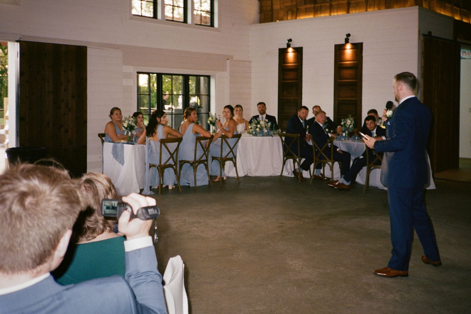 Guest gives a heartfelt speech to the wedding party seated at the head table.