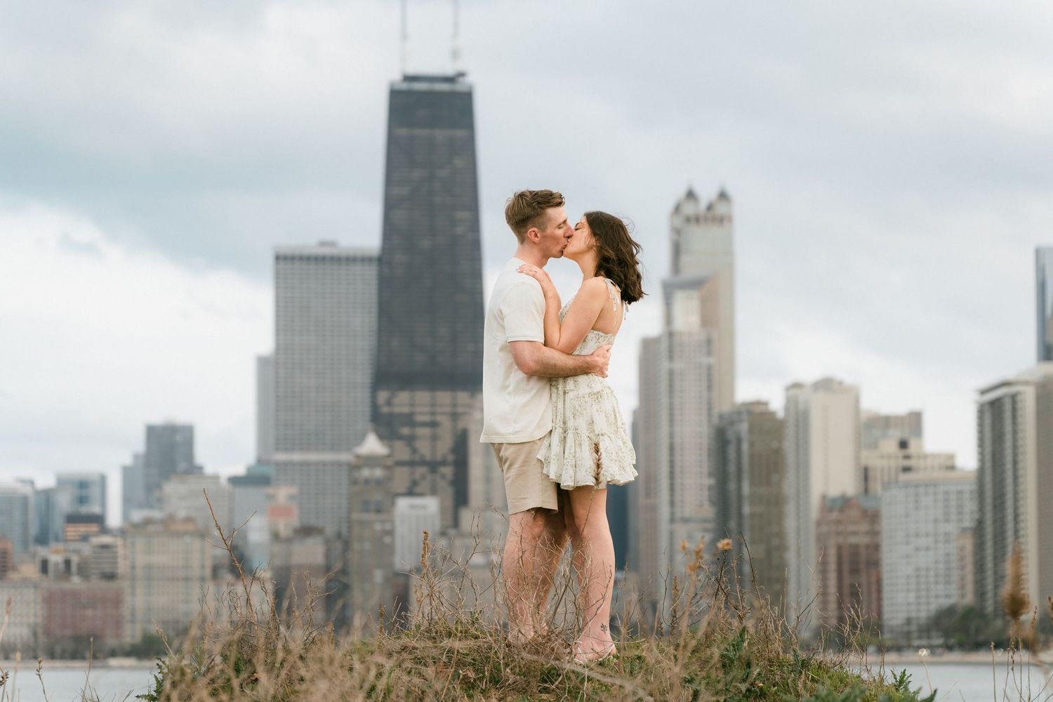 Couple kissing with Chicago city skyline and lake in the background.