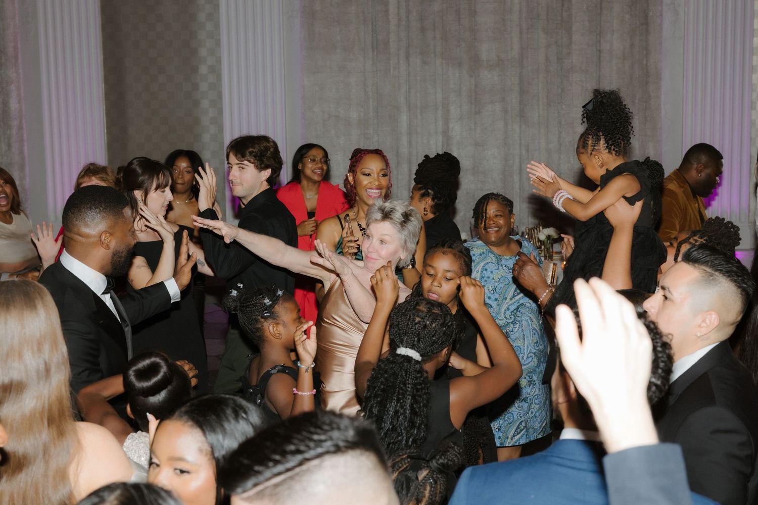 Diverse group of elegantly dressed guests dancing and celebrating at a formal party or prom event.