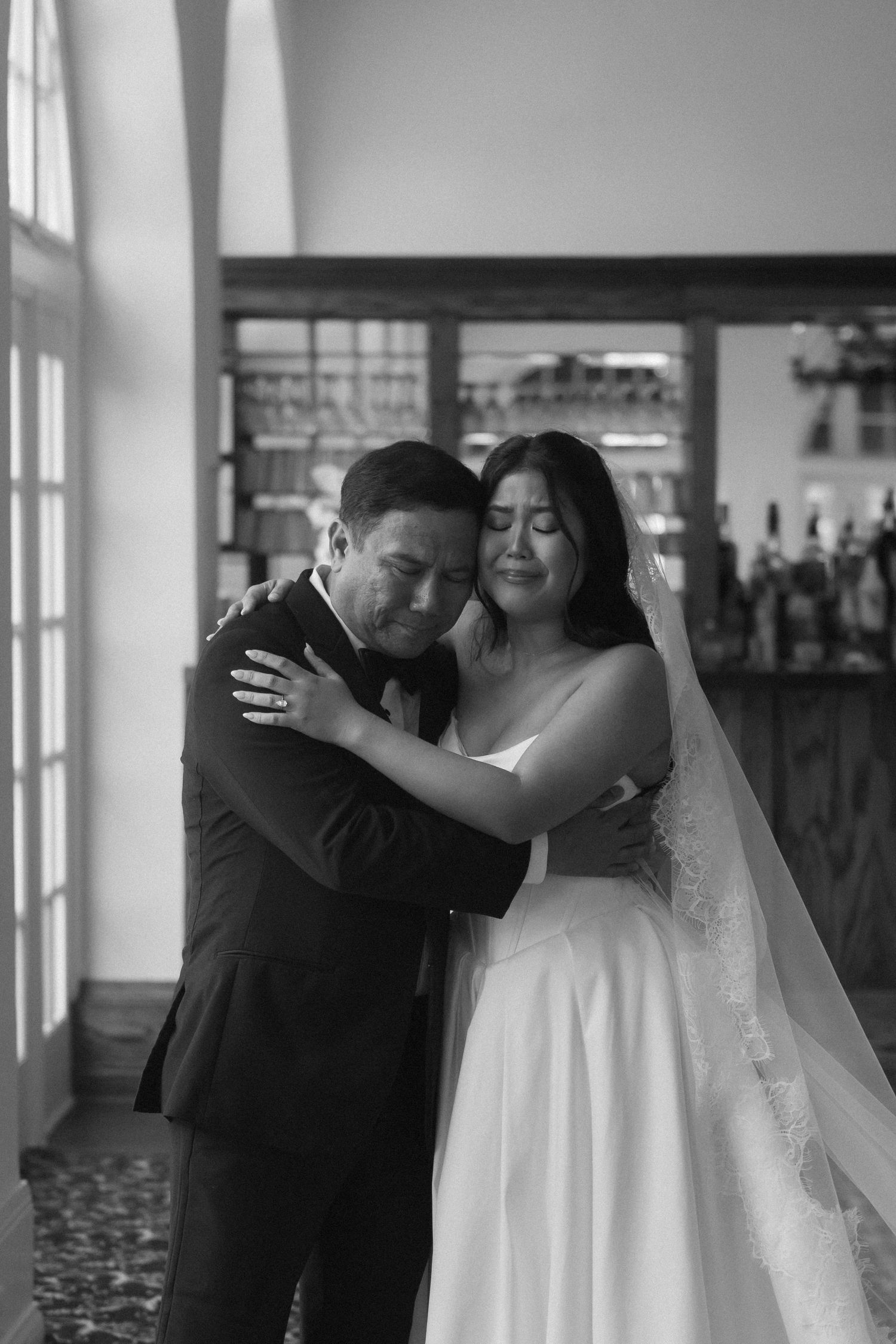 Black and white photo of an emotional bride and groom sharing a tender embrace on their wedding day.