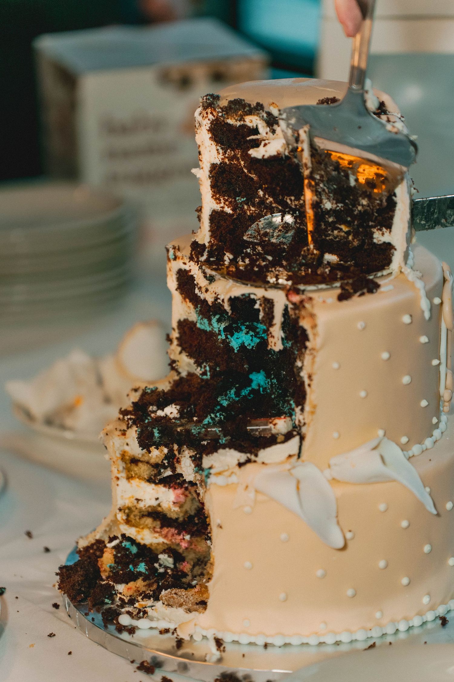 Sliced wedding cake reveals colorful chocolate and blue interior layers at reception.