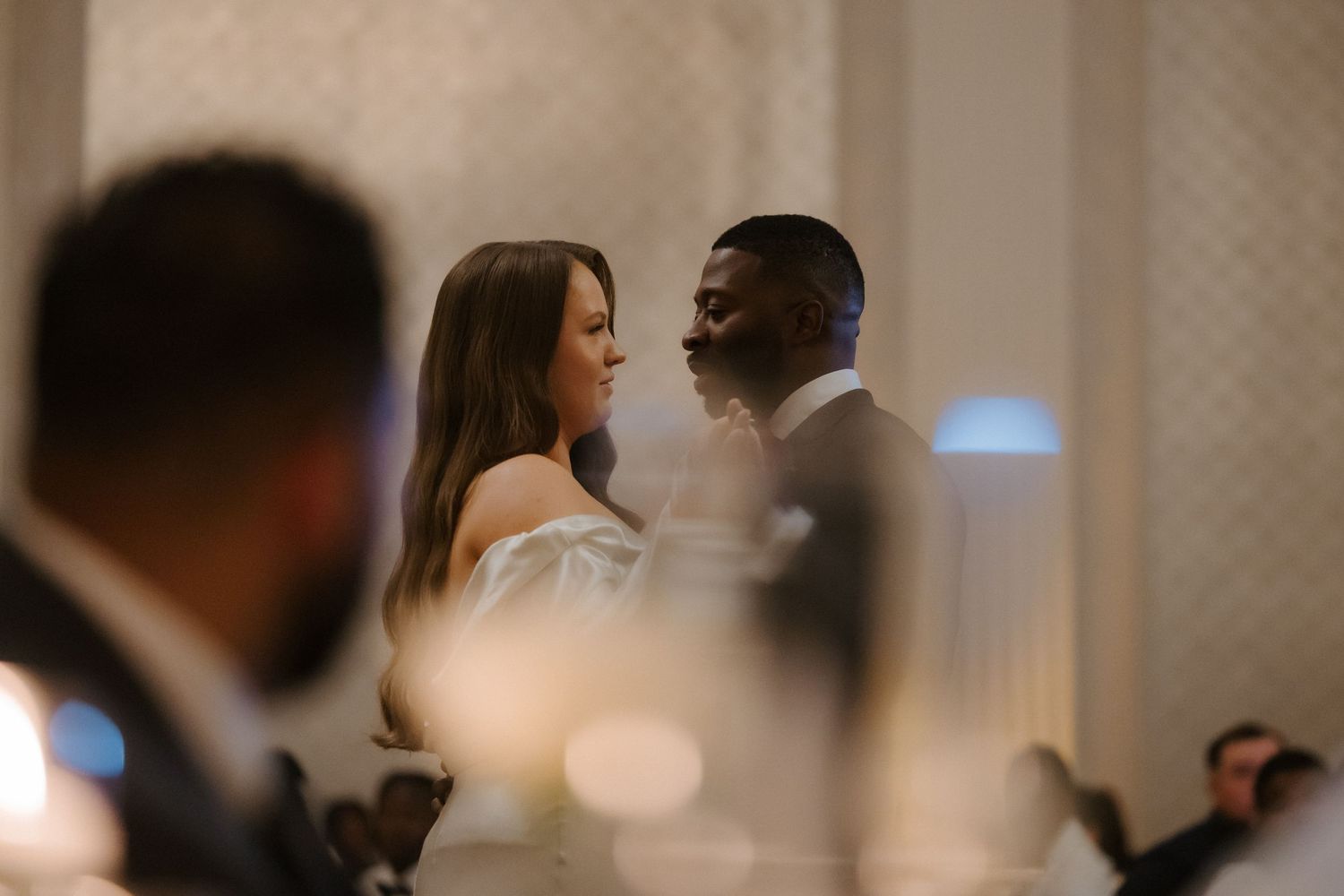 Couple sharing an intimate moment at a formal wedding reception in an elegant venue.