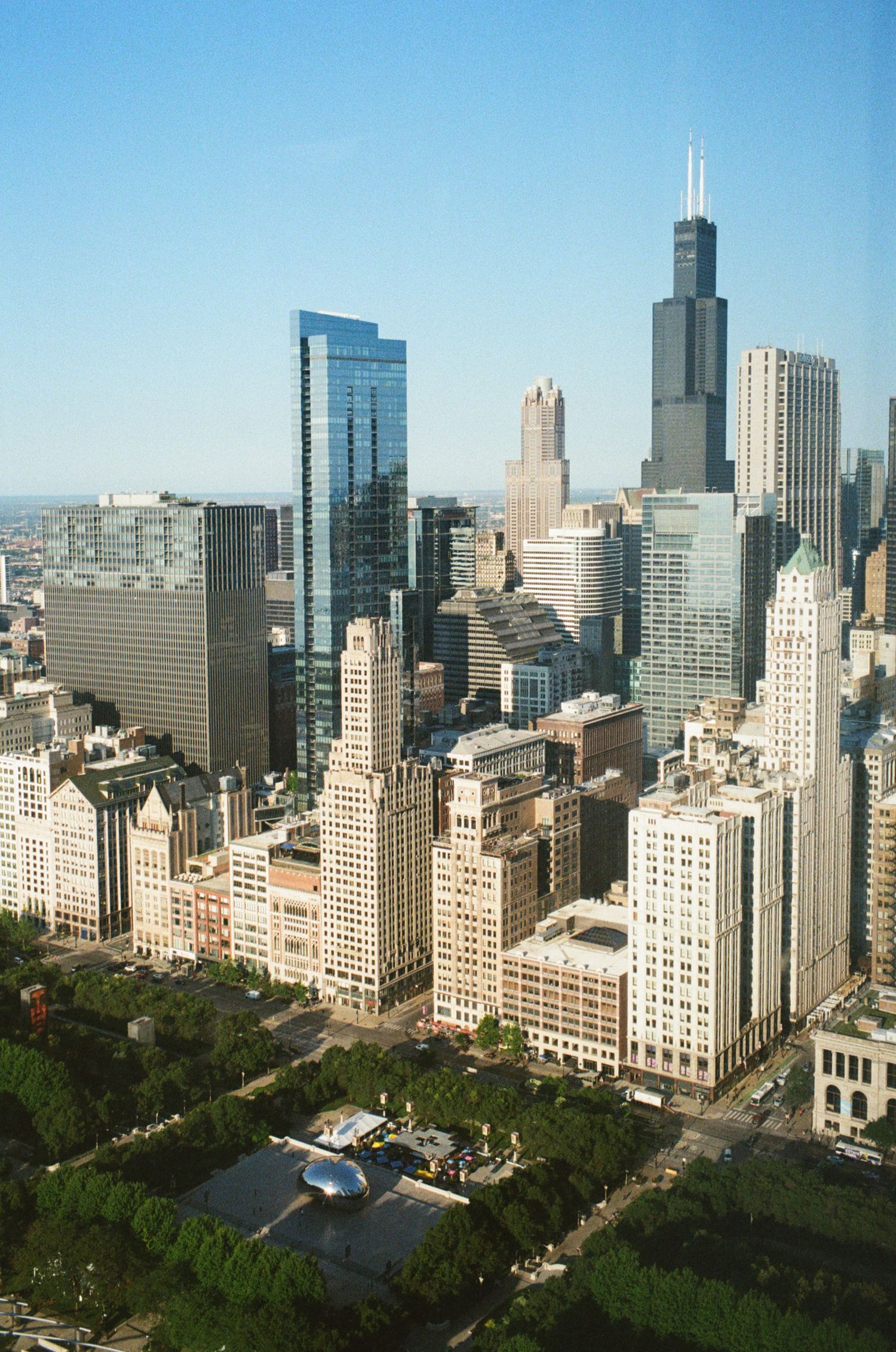 Aerial view of Chicago skyline featuring Willis Tower and Millennium Park on a clear sunny day.