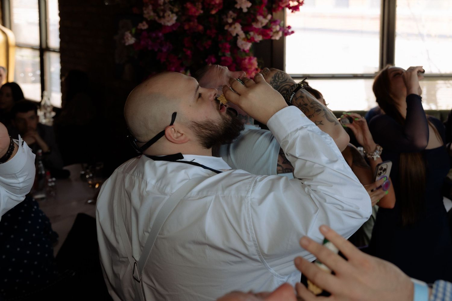 Two people share an emotional embrace at a wedding reception with floral decorations in the background.