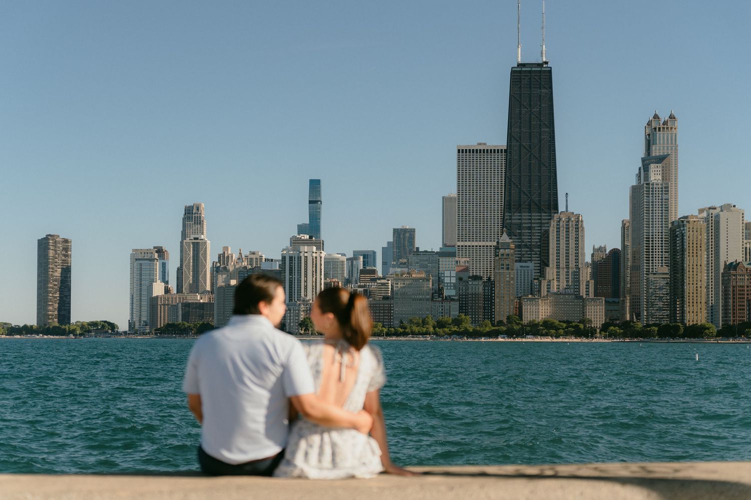 Couple sitting closely on Lake Michigan seawall admiring the beautiful Chicago city skyline.