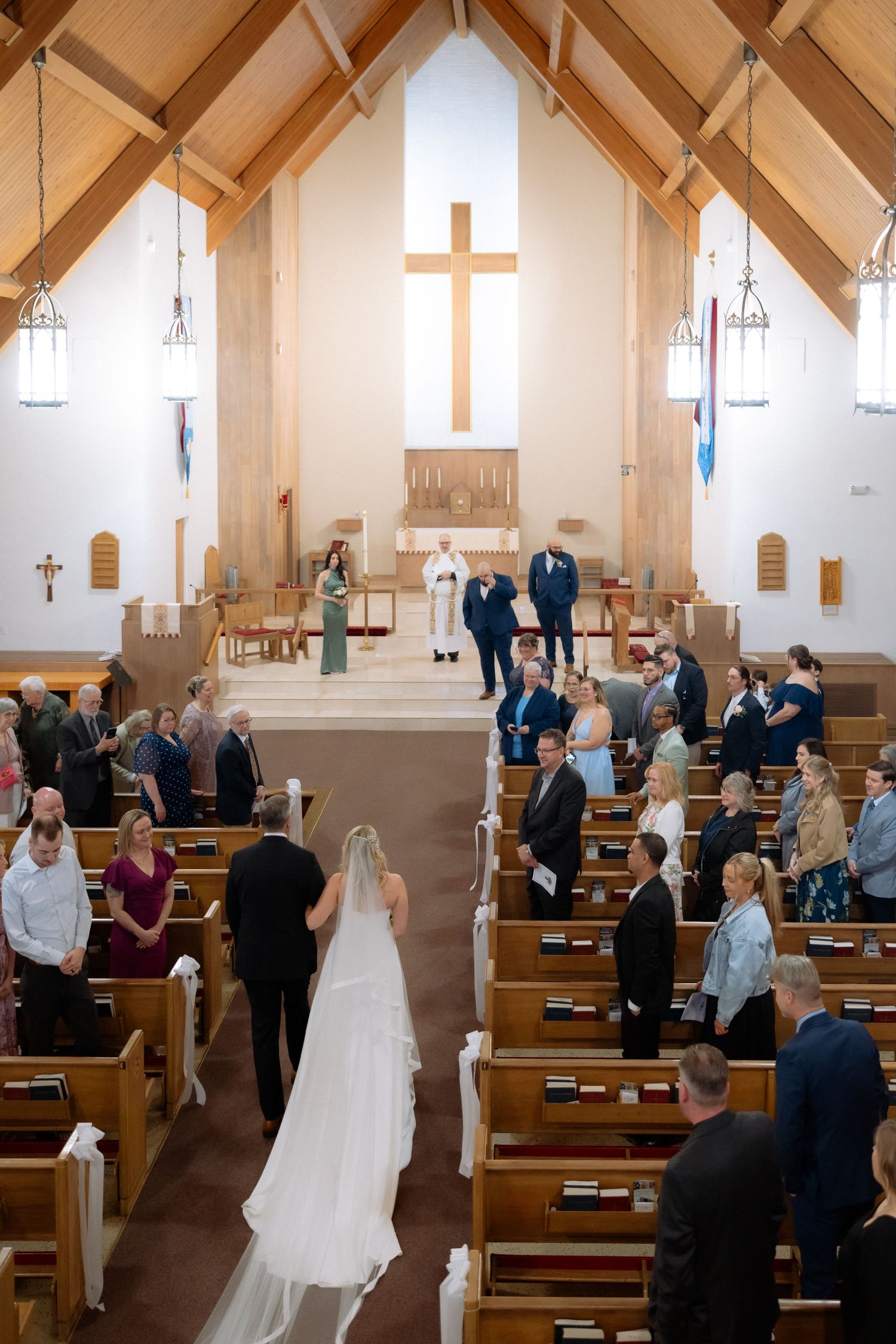 Bride walking down the aisle in a church wedding ceremony with guests standing and groom waiting at the altar.