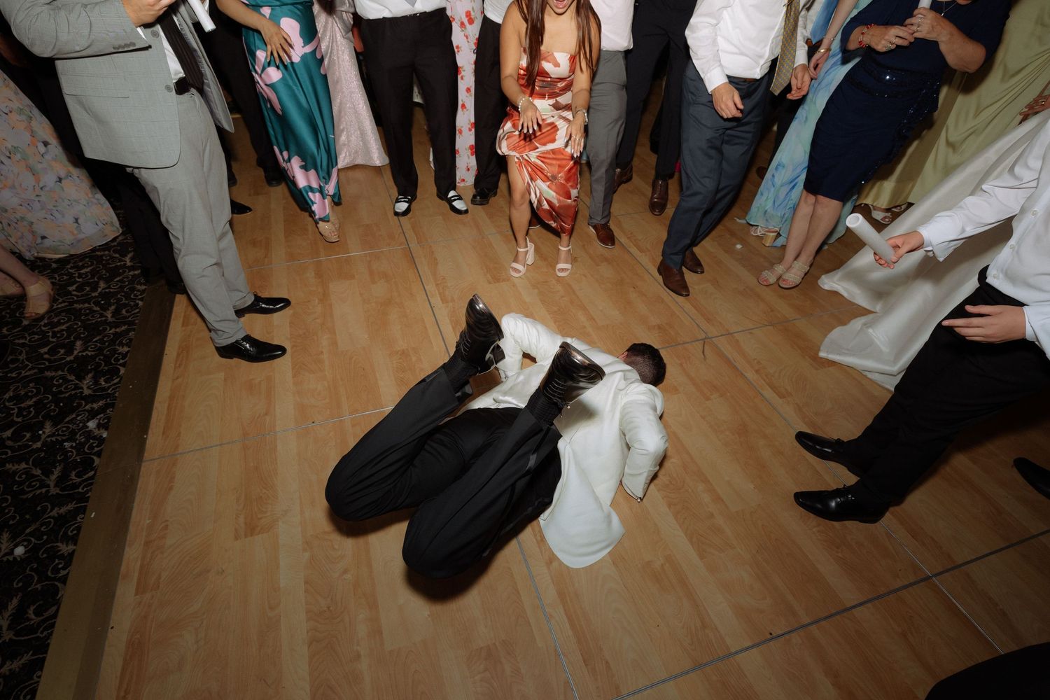 Wedding guests circle the dance floor as bride and groom share a romantic dip during reception.