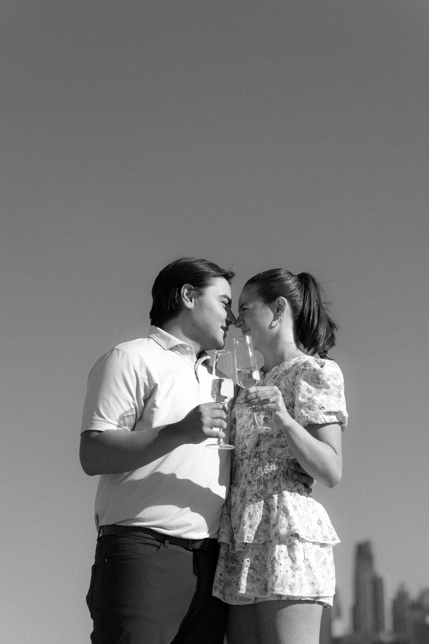 Black and white romantic photo of couple about to kiss while holding champagne flutes.