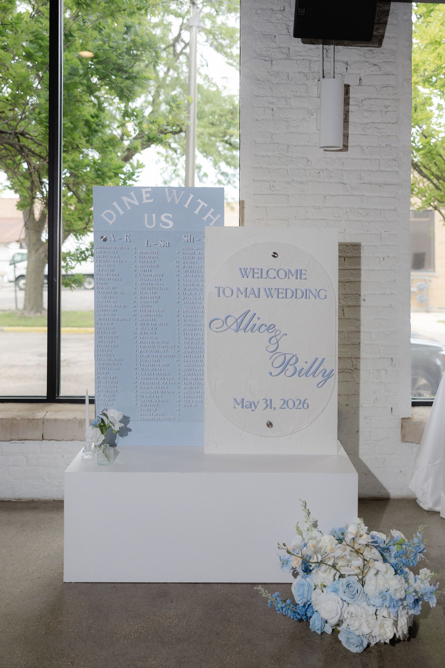 Elegant wedding welcome sign for Alice and Billy, May 31 2026, with seating chart and blue floral arrangements.