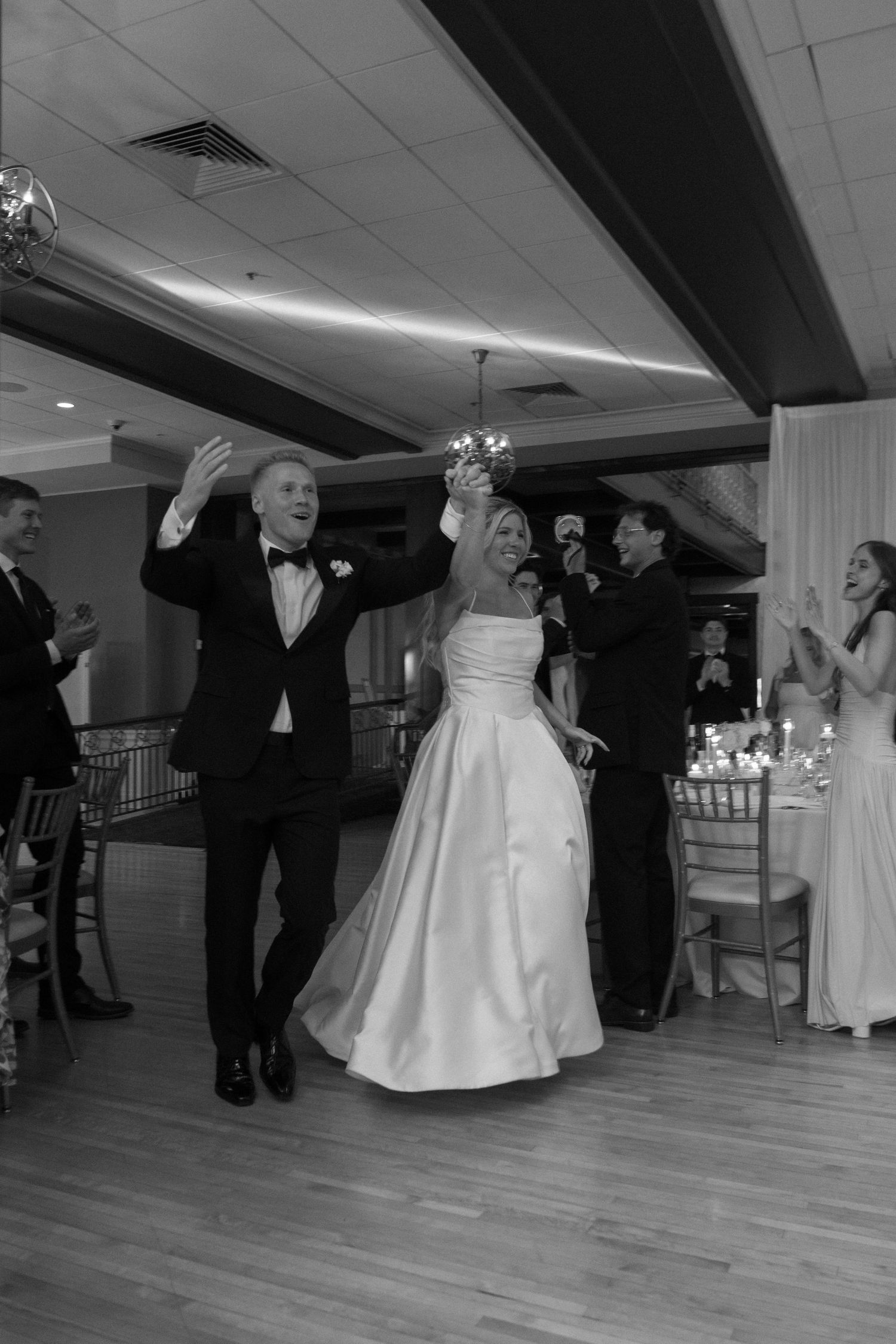 Black and white photo of bride and groom making a grand entrance at their wedding reception.