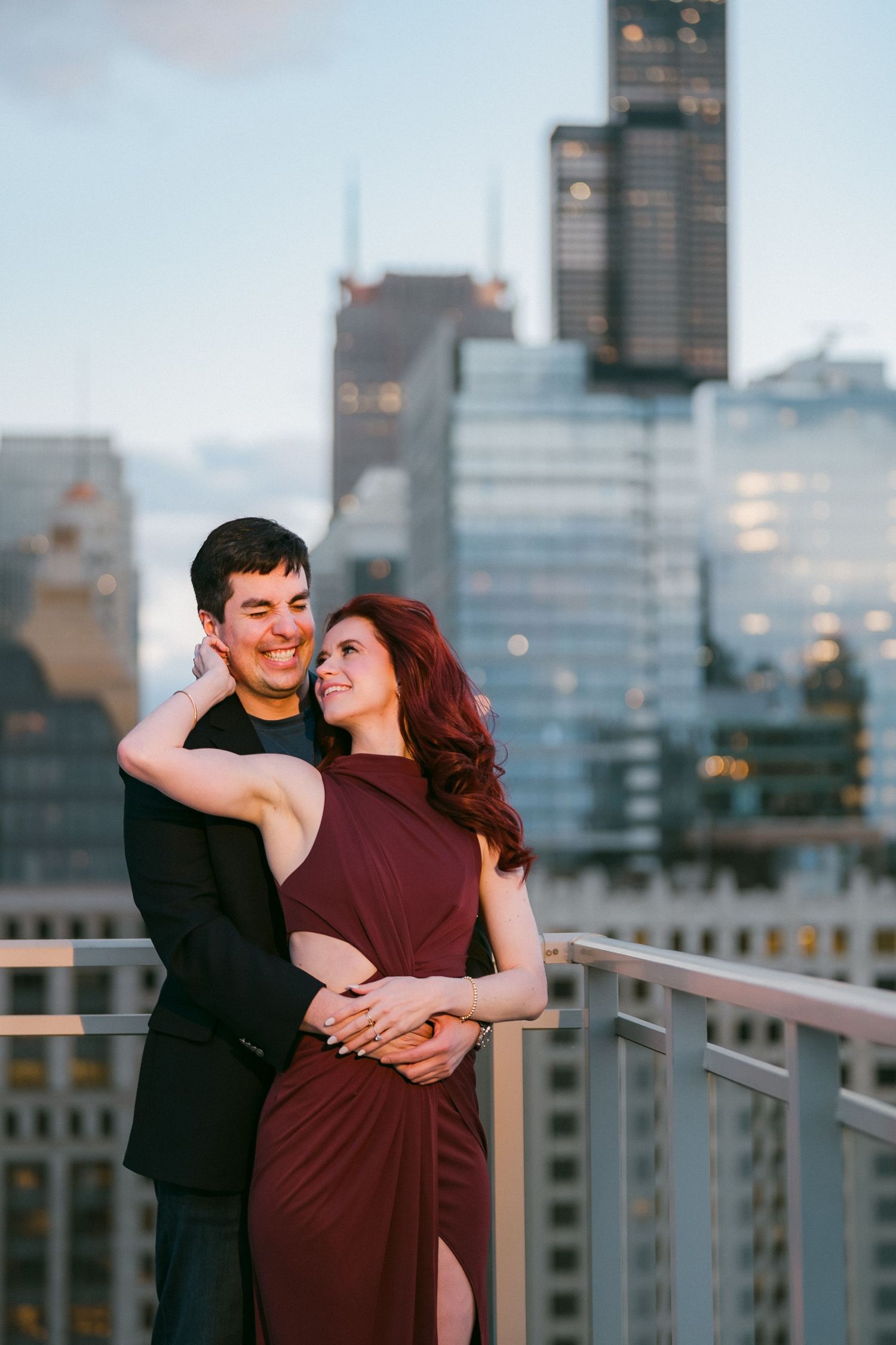 Couple embracing on Chicago rooftop at dusk with stunning city skyline behind them.