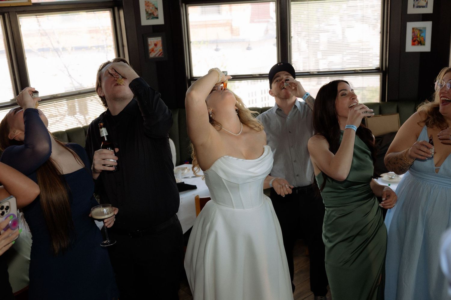 Bride and wedding guests drinking and celebrating at indoor wedding reception.