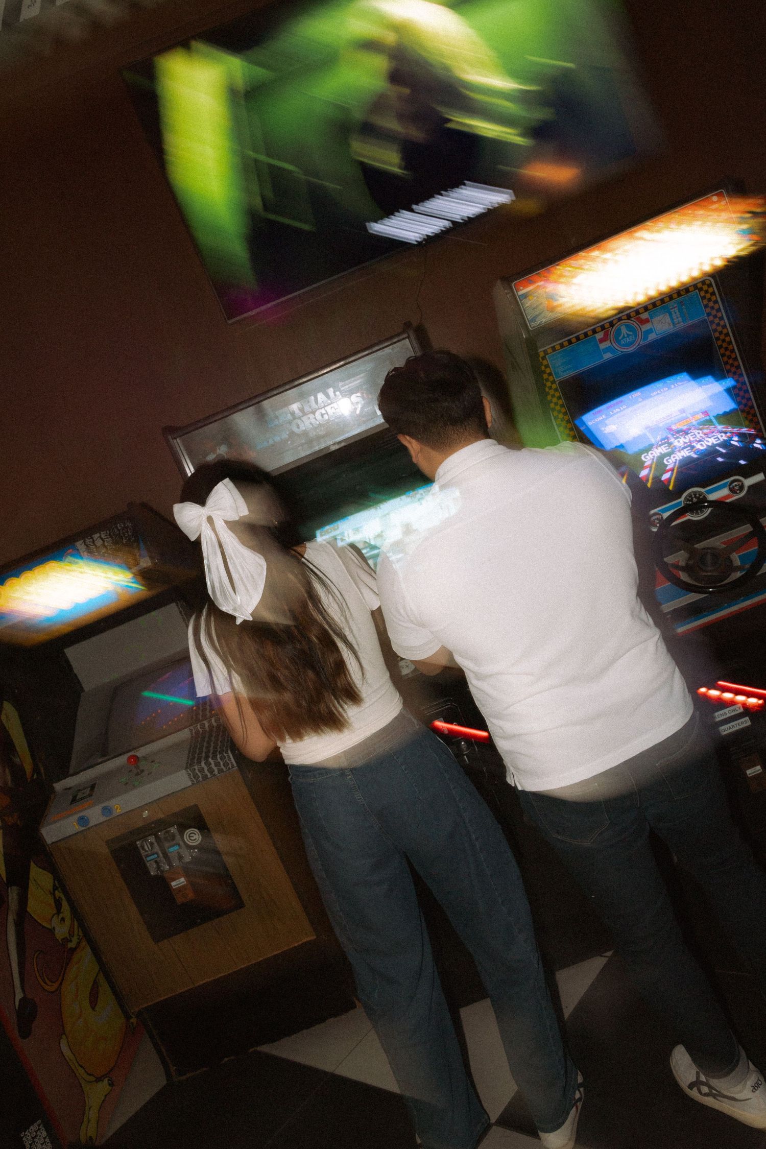 Couple playing a vintage arcade game together in a colorful retro arcade venue.