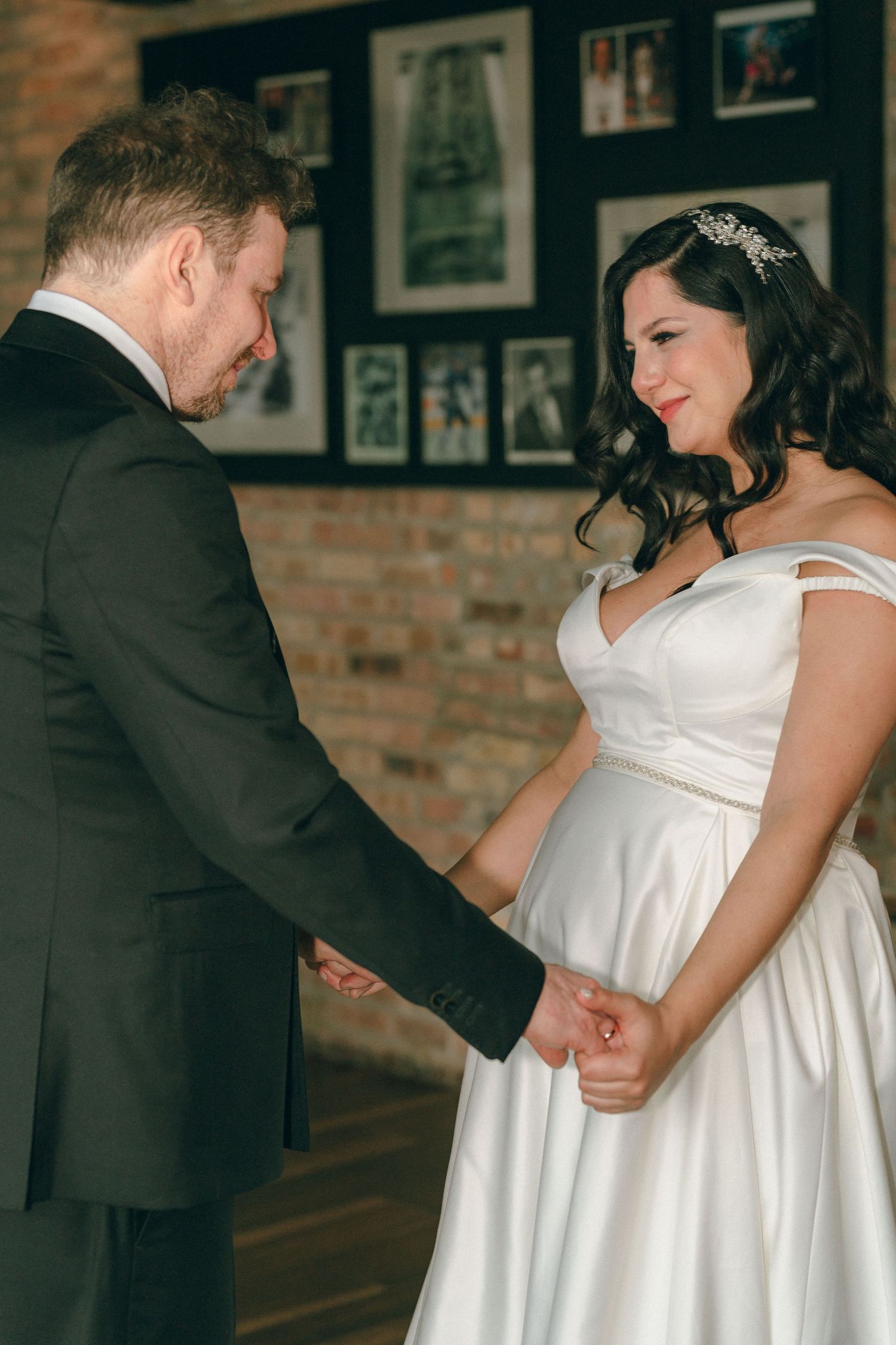 Bride and groom share tender moment holding hands during wedding reception at venue.