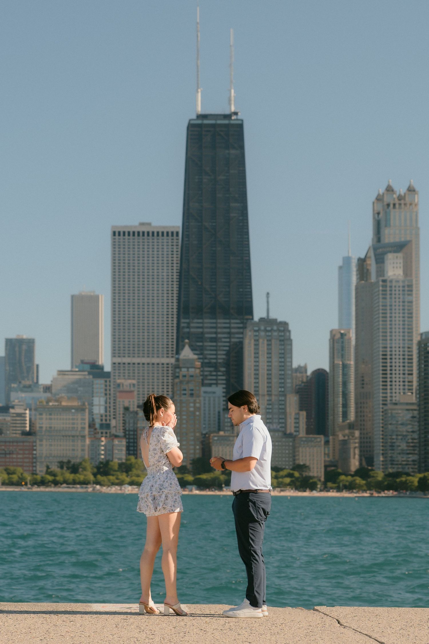 Couple standing together by Lake Michigan with Chicago city skyline behind.