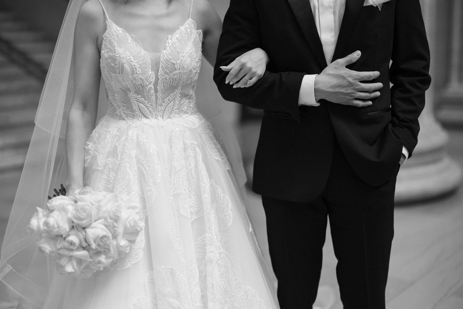 Elegant black and white photo of a bride and groom walking together on their wedding day.