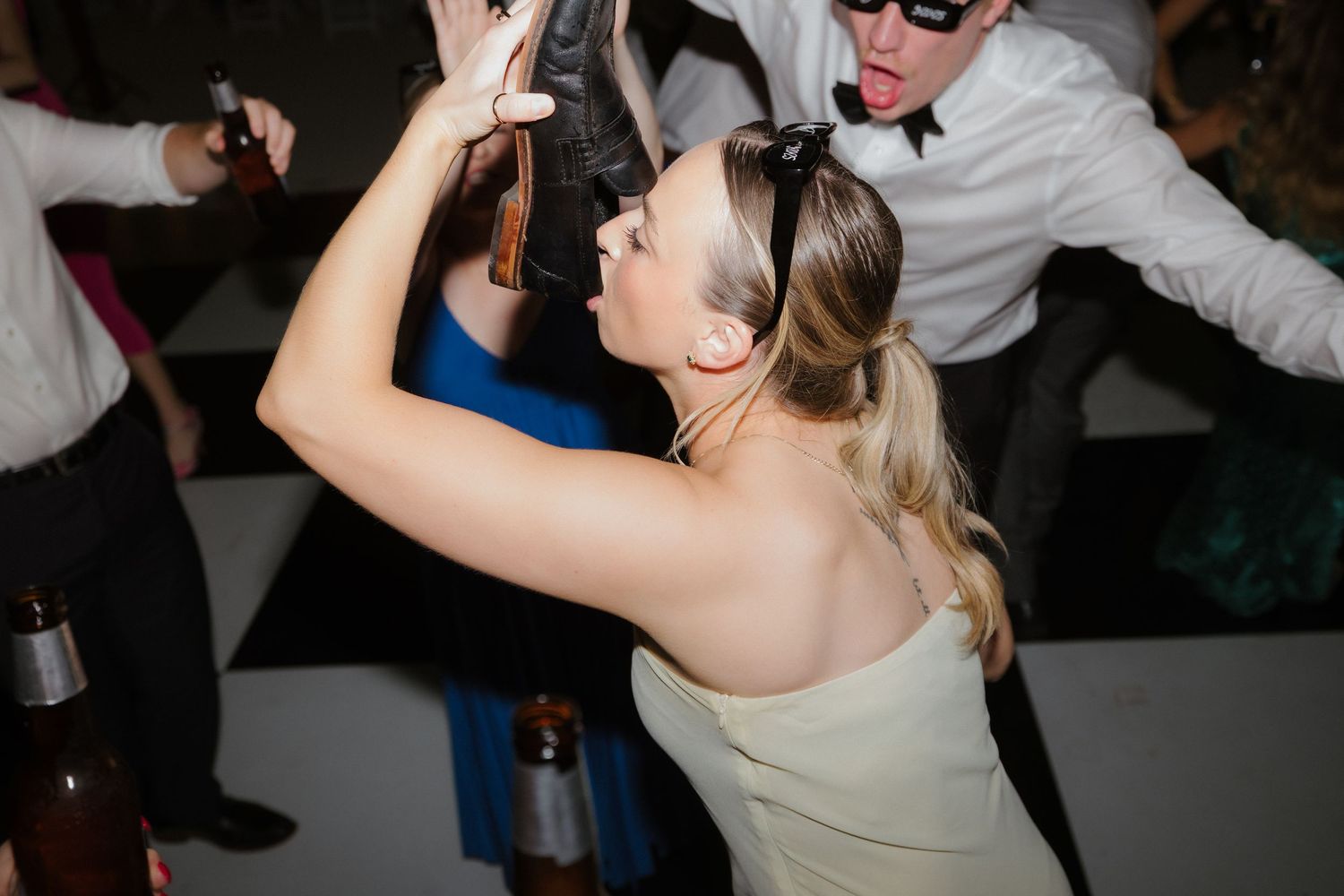 Bride in white dress dancing energetically with guests at a lively wedding reception party.