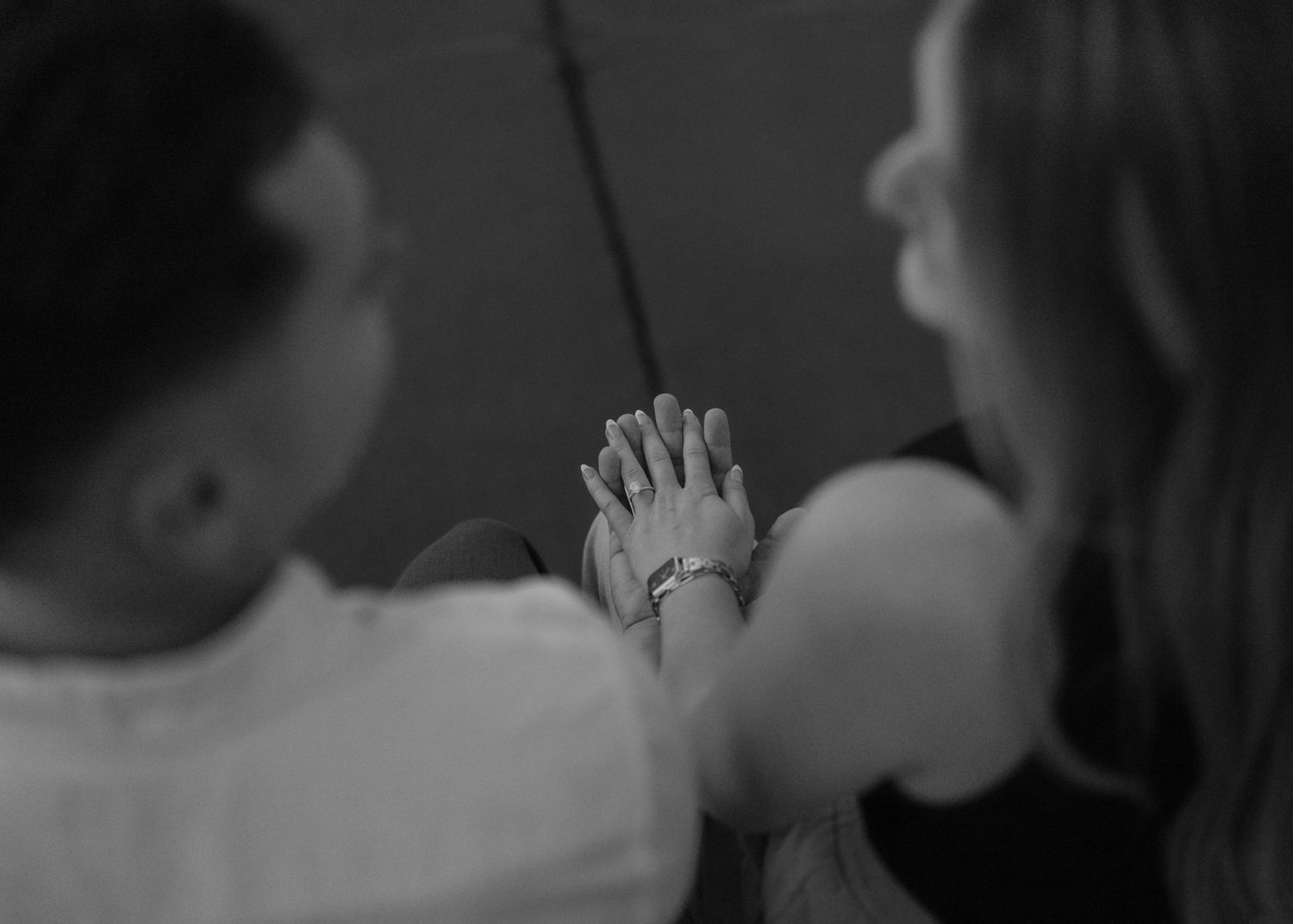 Black and white photo of two people holding hands, showing a tender moment of connection and togetherness.