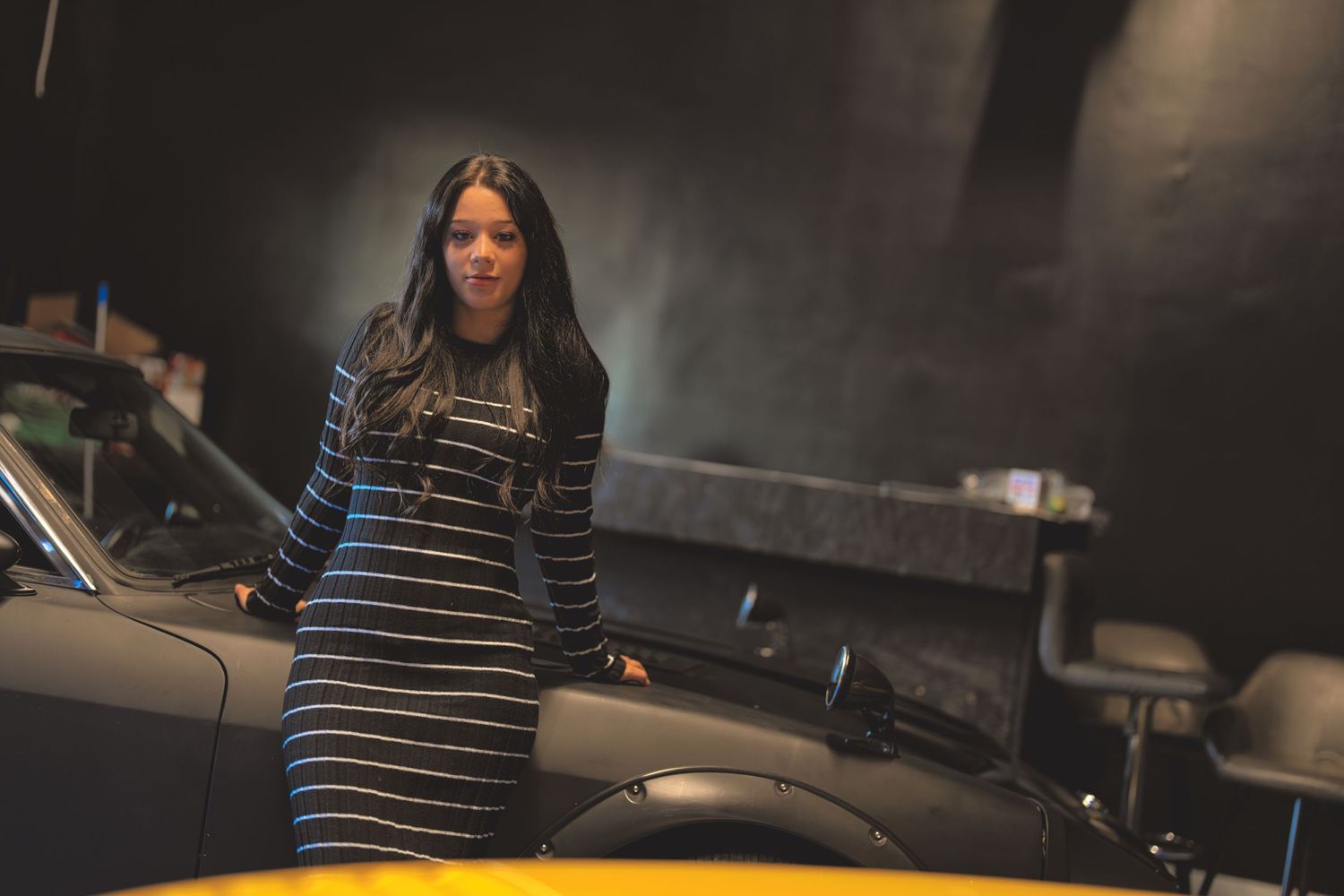 Woman leaning on a car.