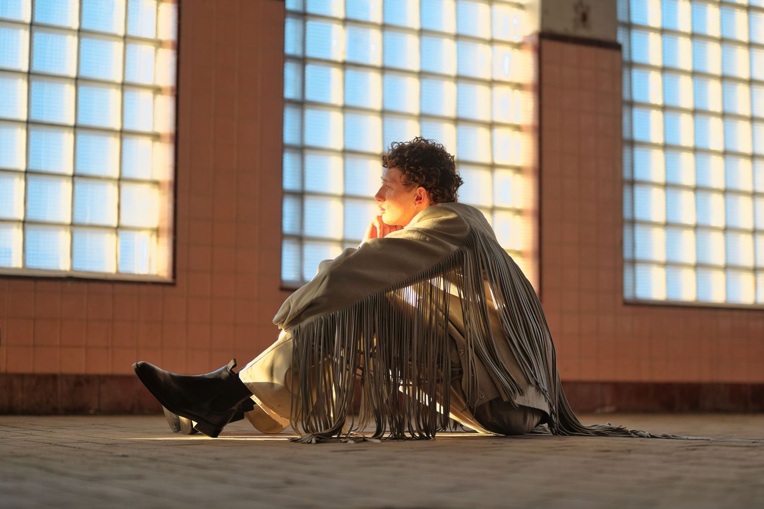 Man sitting on floor looking at the sunset.