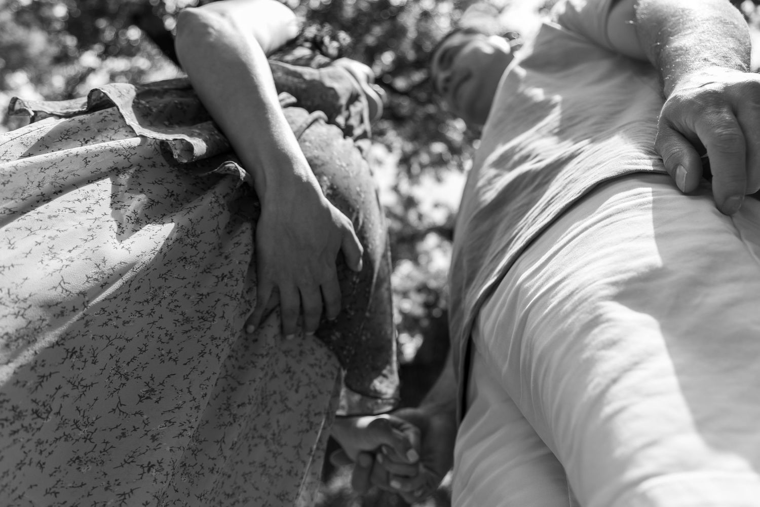 Black and white photo of hands gripping a stone ledge, with draped fabric visible in the background.