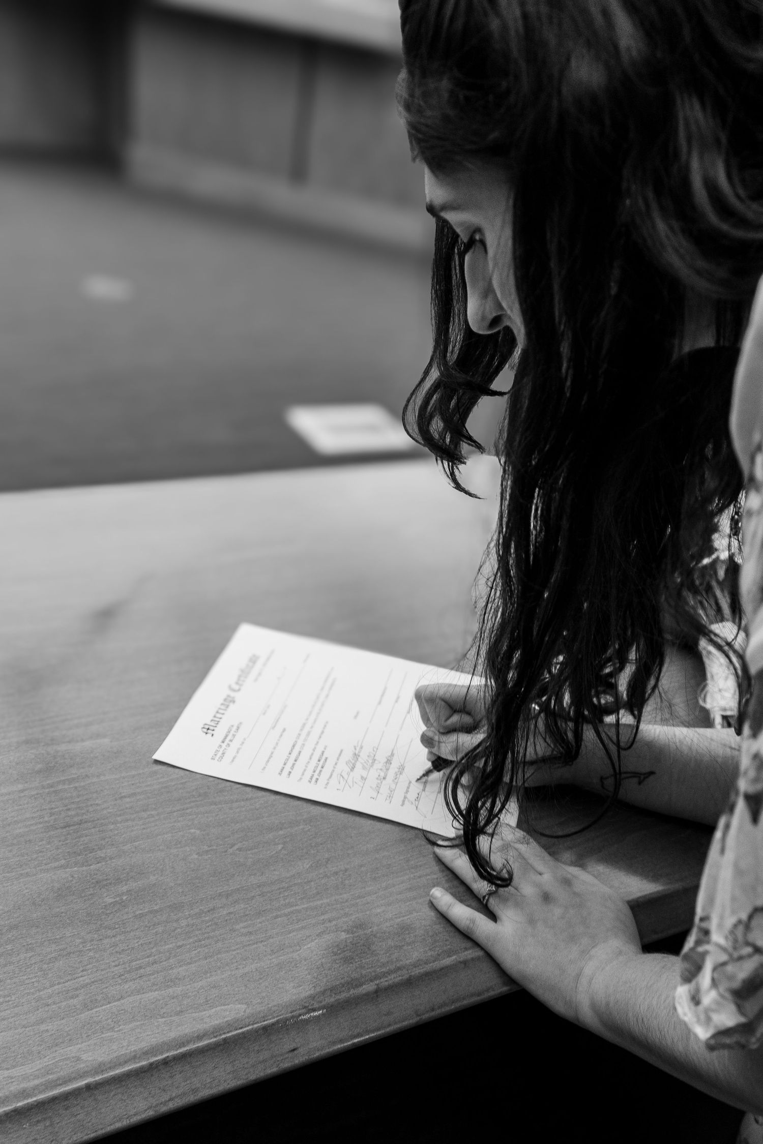 Bride signing marriage certificate at courthouse in black and white photo.