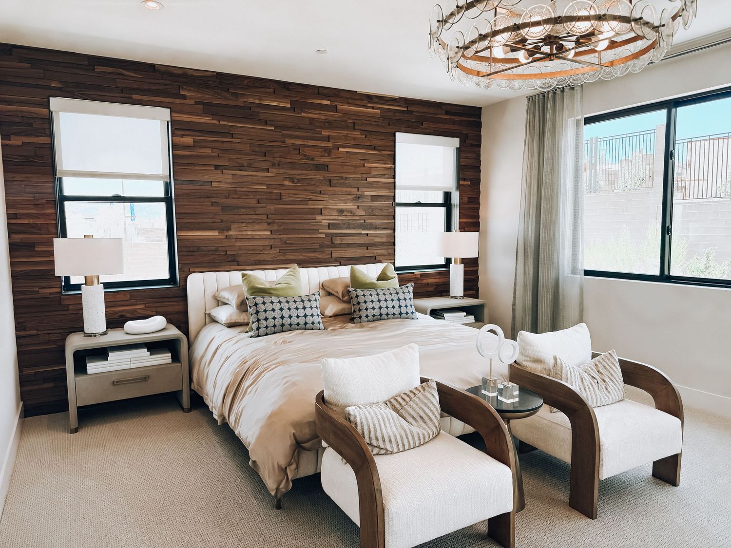 Rustic bedroom with reclaimed wood accent wall, white bedding, wooden furniture, and an elegant chandelier.