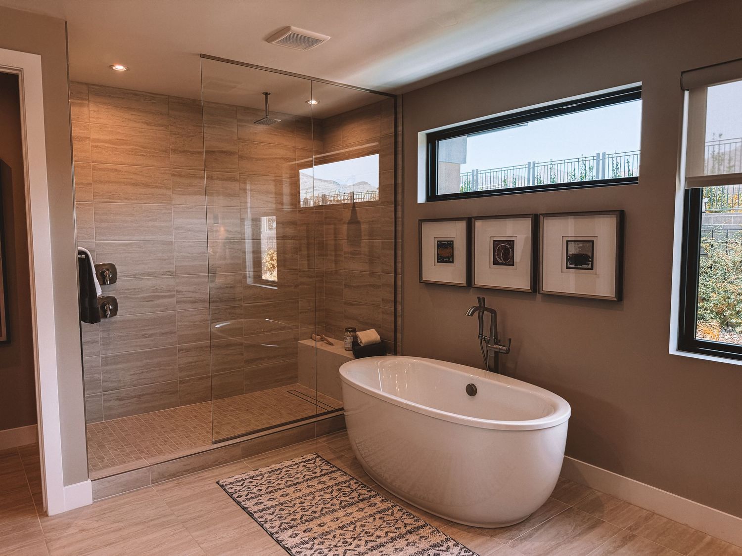 Modern luxury bathroom featuring a freestanding soaking tub, walk-in glass shower with tile walls, and large windows.