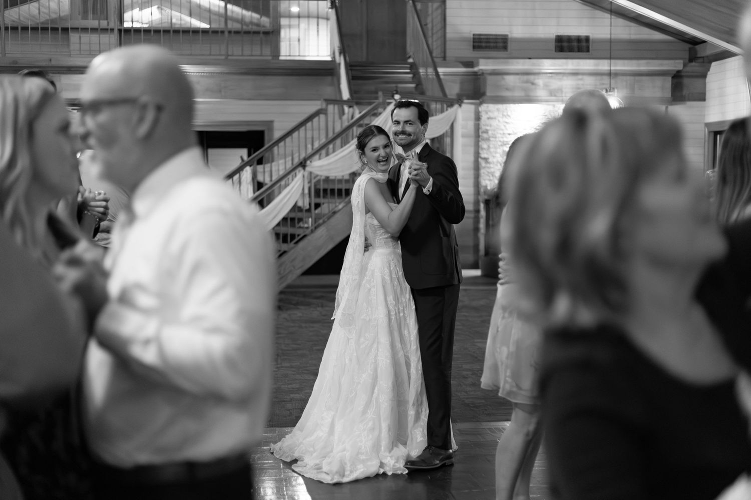 Black and white photo of a bride and groom sharing their first dance at a wedding reception.
