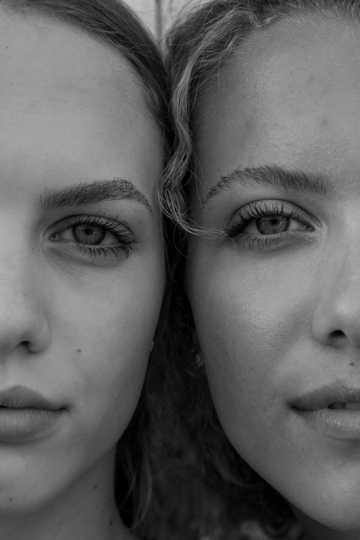 Black and white close-up portrait of two young women with their faces together.